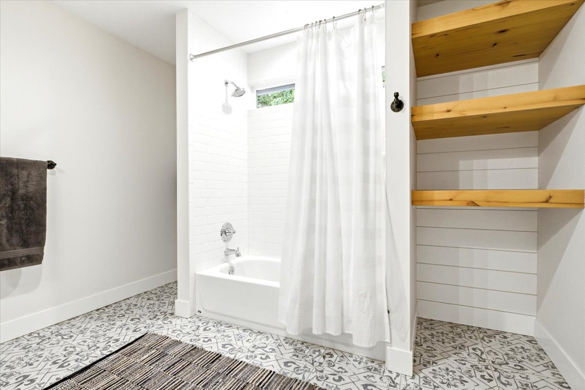 Bathroom featuring a white tub, chrome shower fixtures, and patterned floor tile