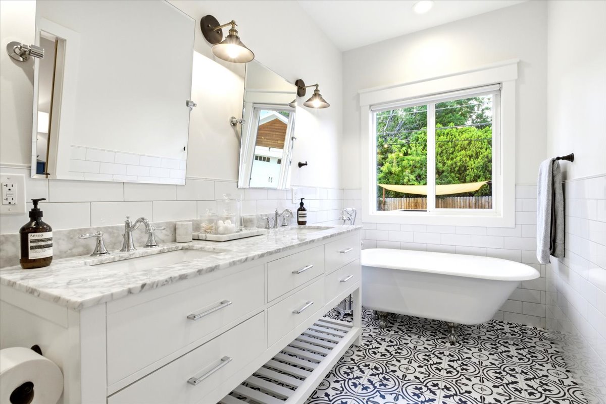 Bathroom featuring a dual vanity with marble countertops, white cabinetry, and polished chrome hardware