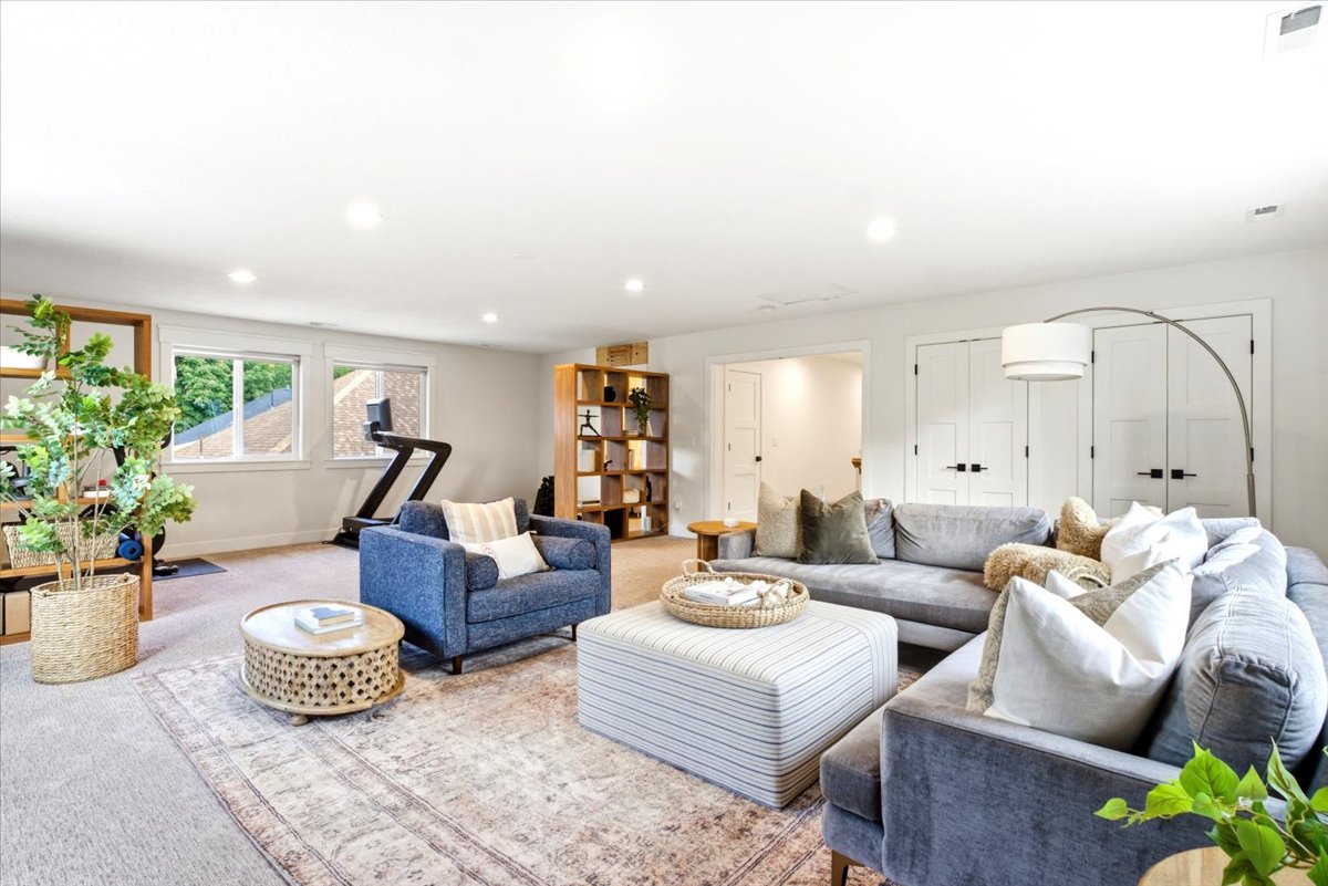 Spacious living area featuring light-colored carpeting, multiple windows, recessed lighting, and built-in shelving units