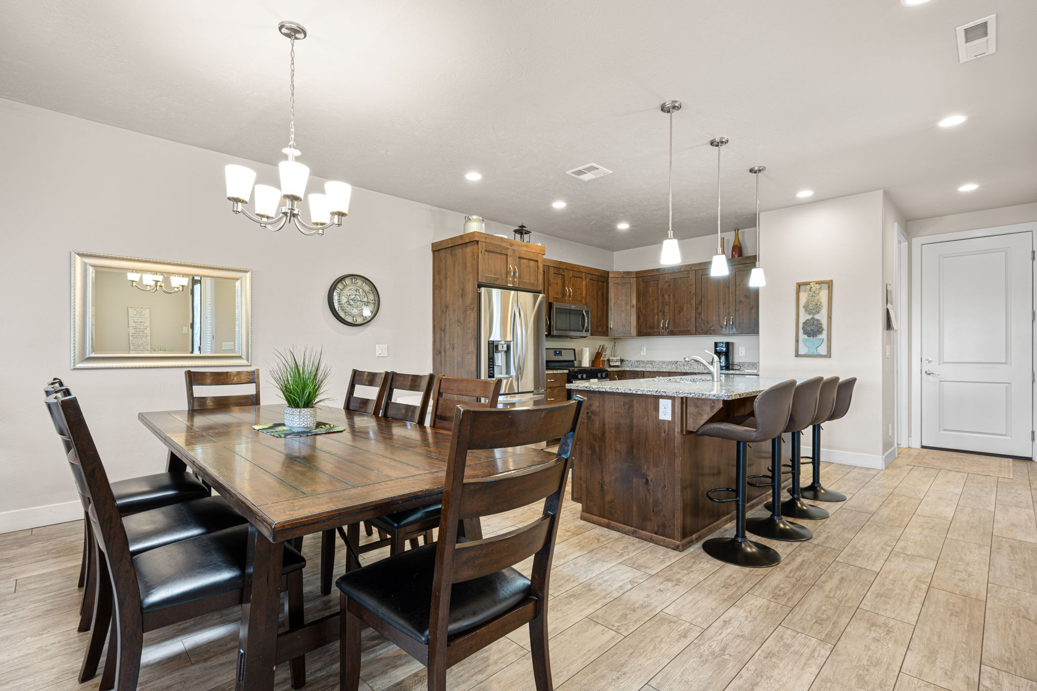 Open-concept living space featuring wood-finish flooring, a kitchen island with seating, pendant lighting, and stainless steel appliances