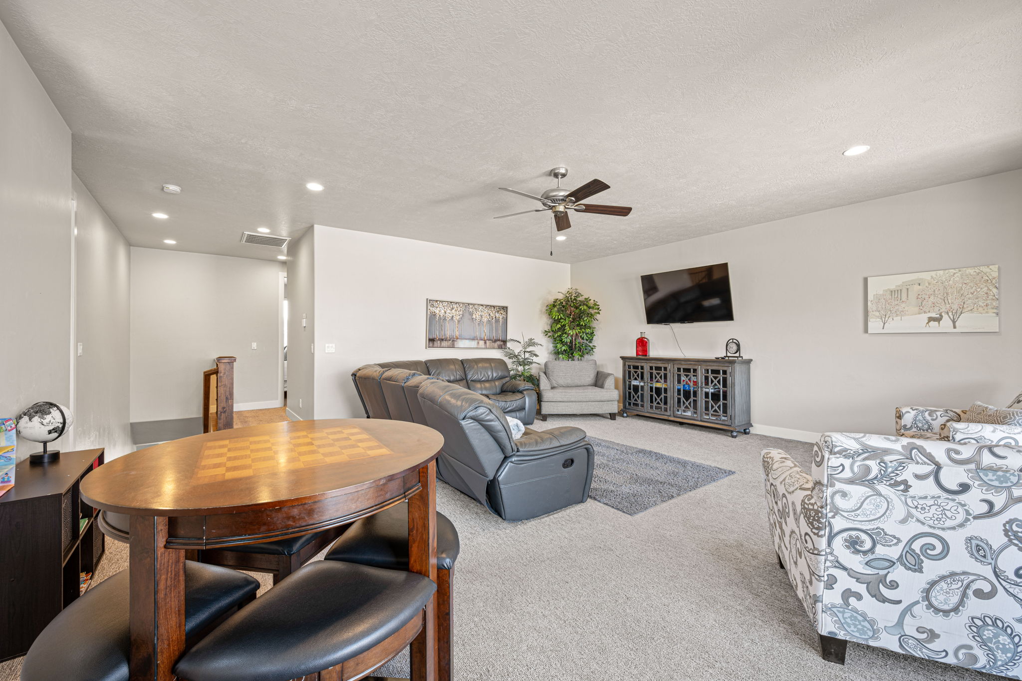 Open-concept living area featuring light-colored carpet flooring, recessed lighting, and a ceiling fan