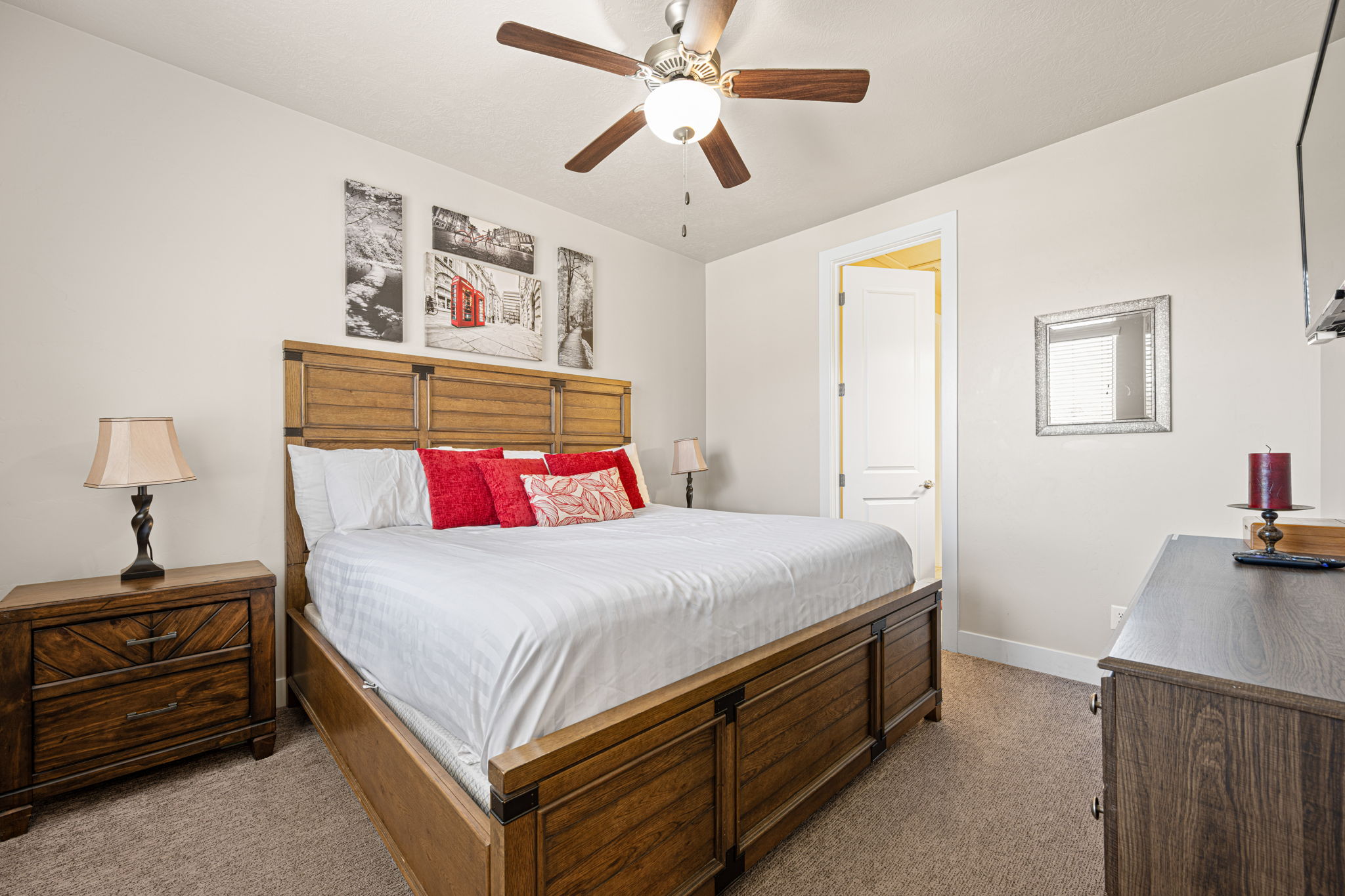 Carpeted bedroom featuring a wooden bed frame with a matching headboard, a wood-finish nightstand, and a ceiling fan with integrated lighting