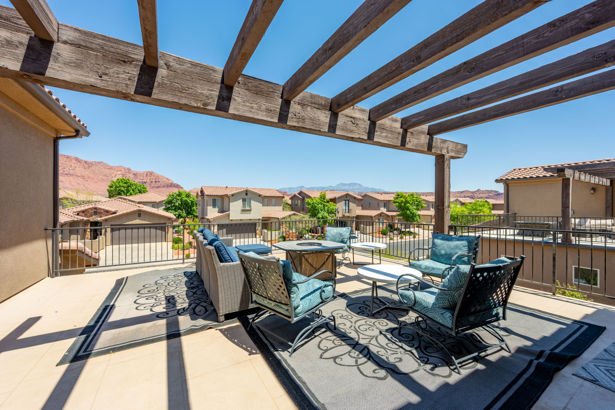 Expansive outdoor patio featuring a wooden pergola, concrete flooring, and metal railing