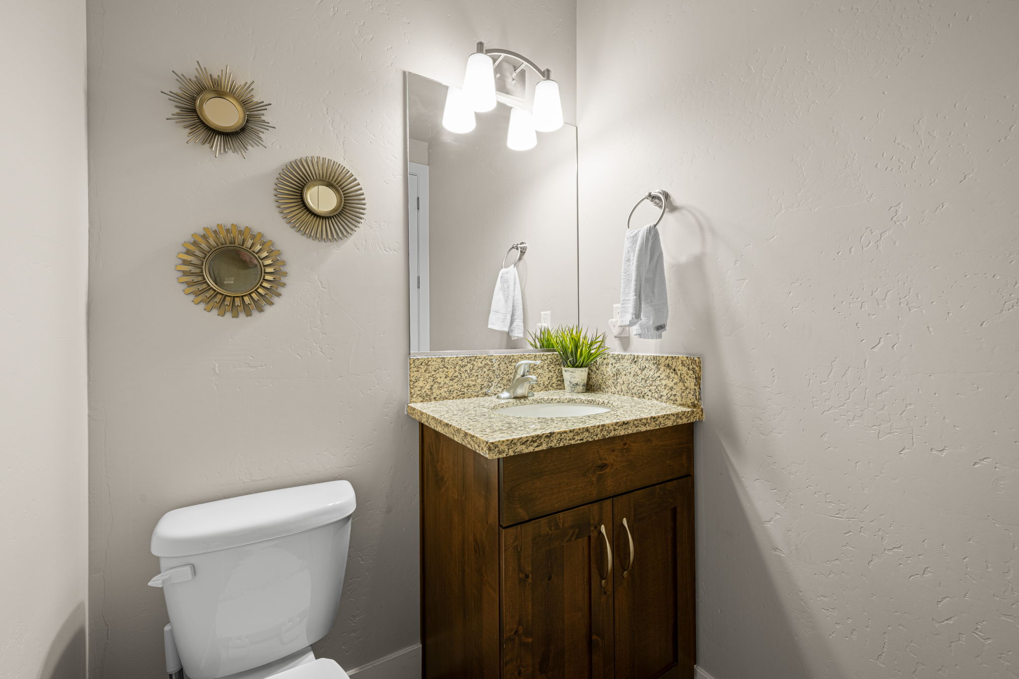 Bathroom featuring a granite-look countertop, undermount sink, and wood-finish vanity with cabinet storage