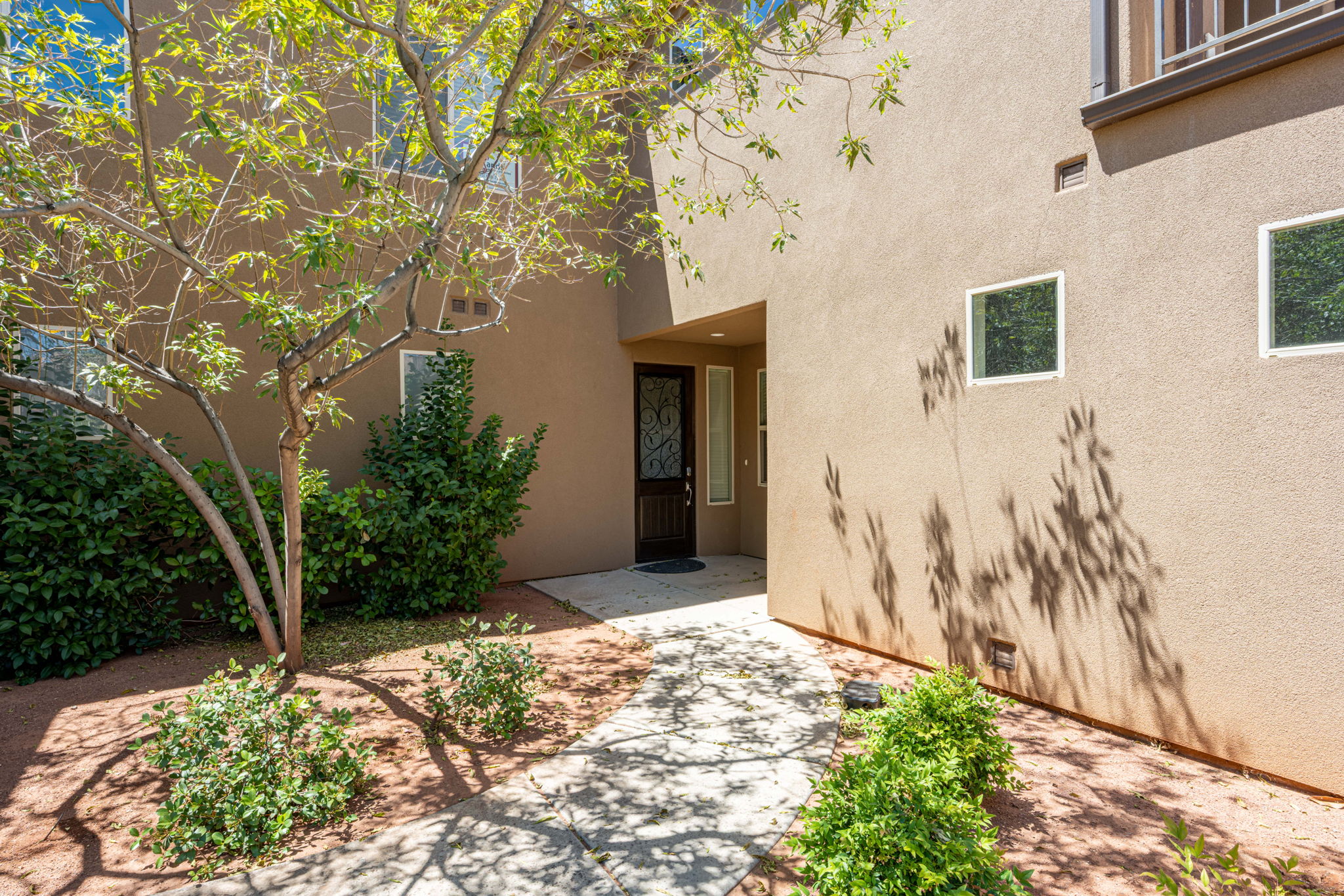 Stucco exterior featuring multiple windows and a dark wood entry door with decorative glass