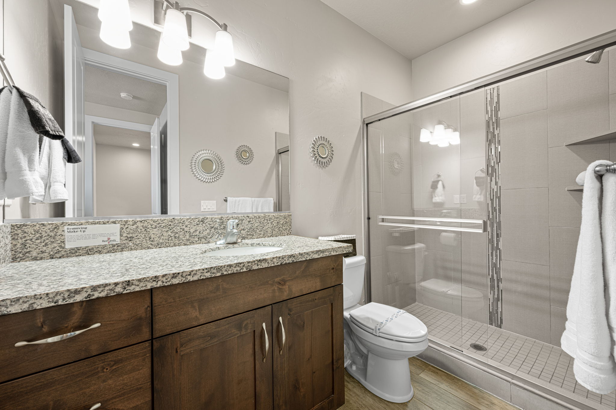 Bathroom featuring a wood-finish vanity with a light-toned countertop, an integrated sink, and a large mirror