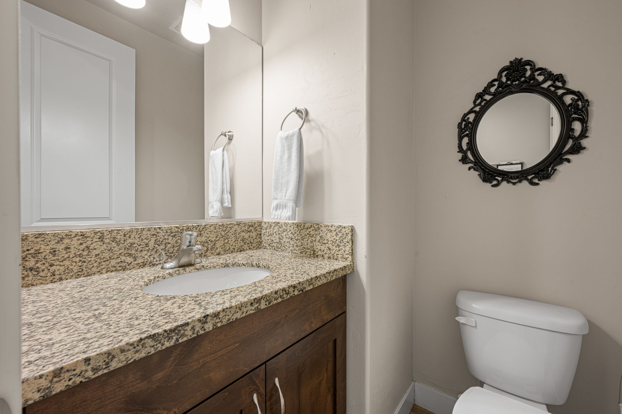 Bathroom vanity featuring a granite countertop with an integrated sink, wood-finish cabinetry, and a chrome faucet