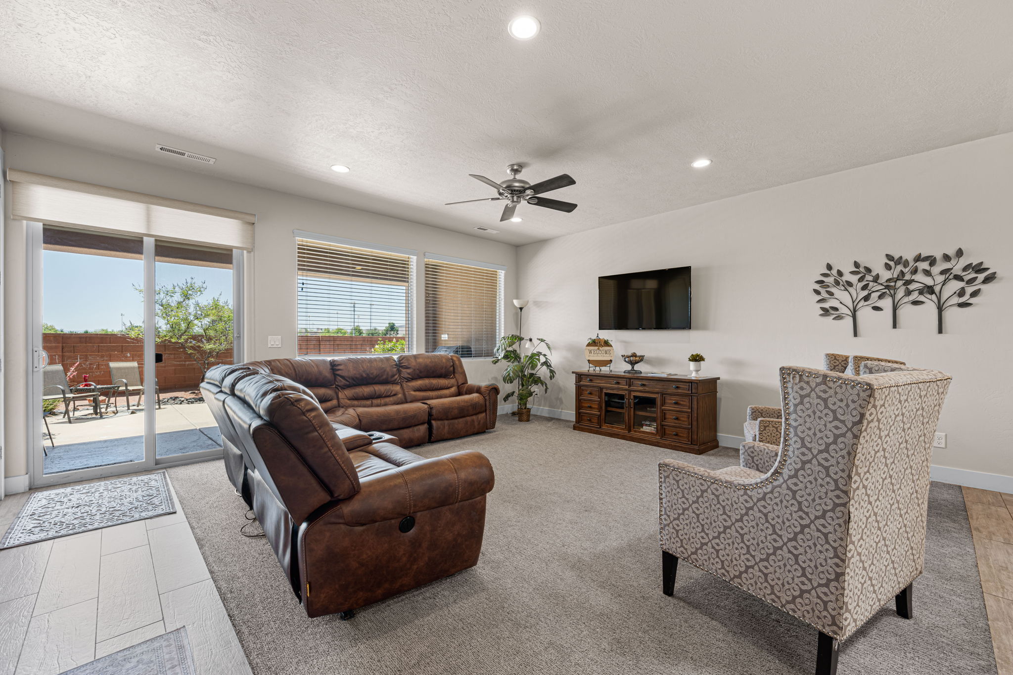 Open-concept living area with light gray carpeting and a ceiling fan