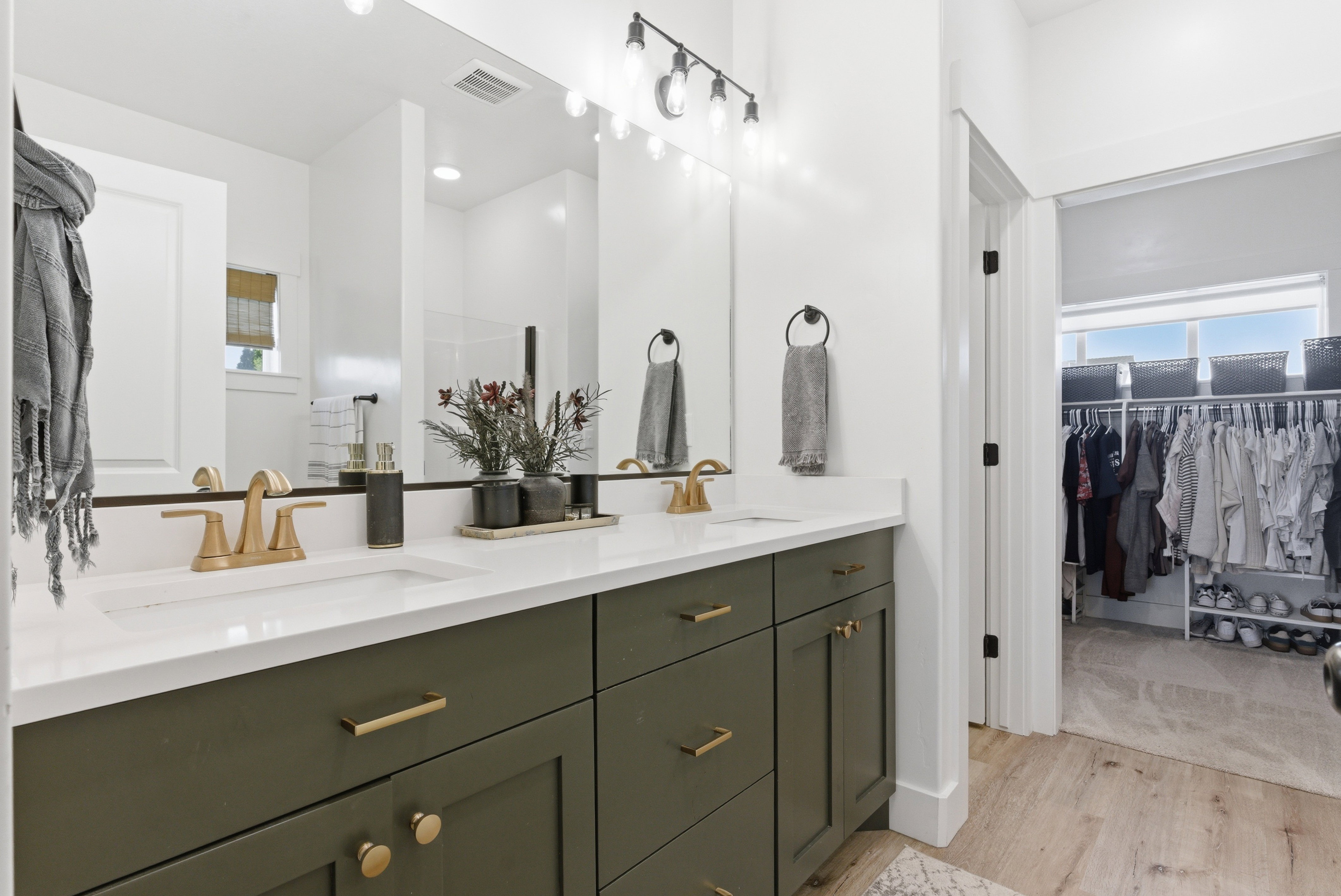 Double vanity with white countertop, matte brass fixtures, and olive green cabinetry
