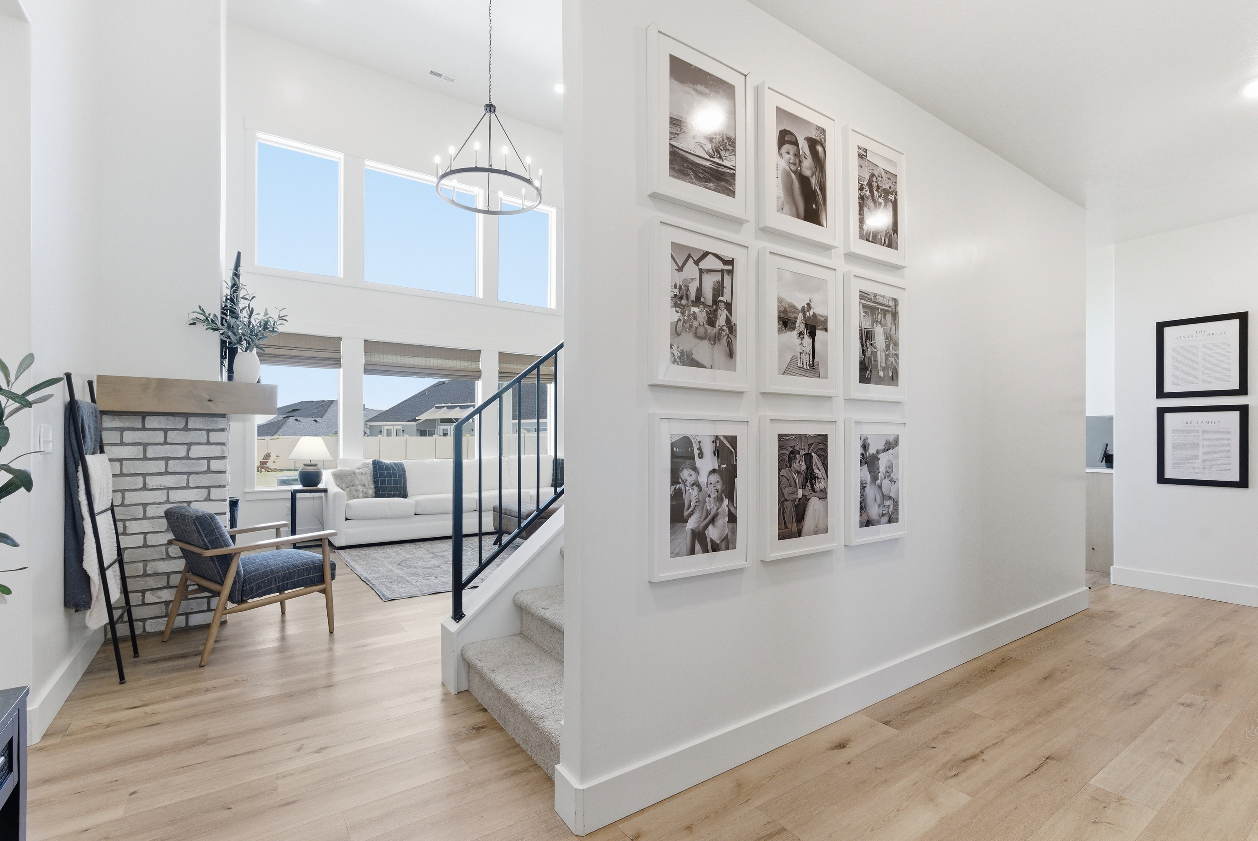 Two-story entry featuring light wood-finish flooring, a contemporary chandelier, and an open staircase with black metal railings