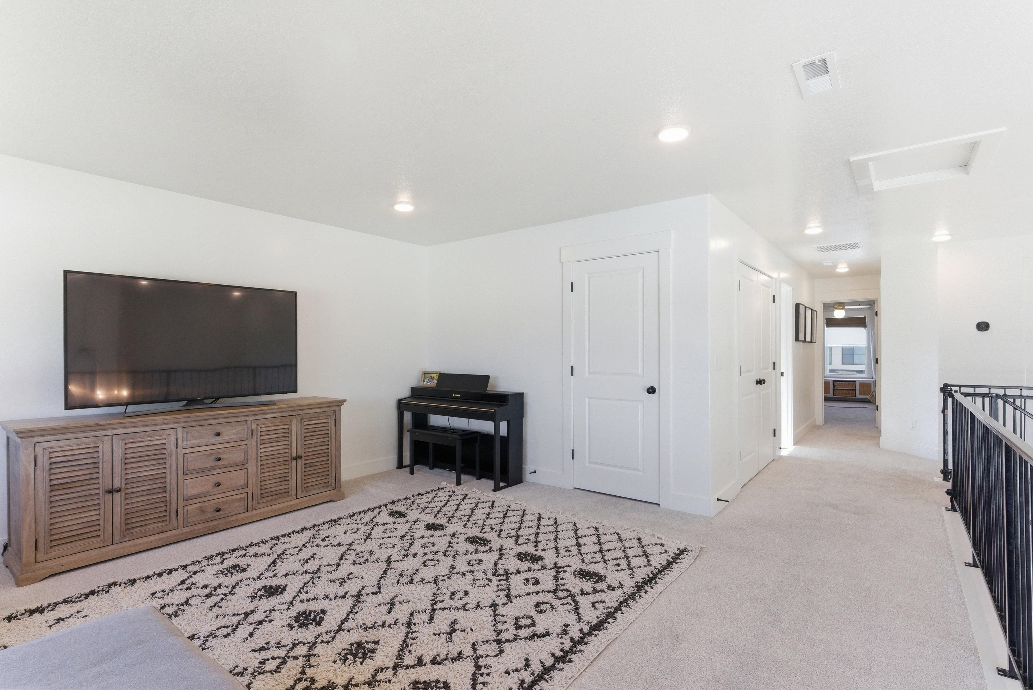 Carpeted entertainment area featuring recessed lighting, white walls, and white doors with dark hardware