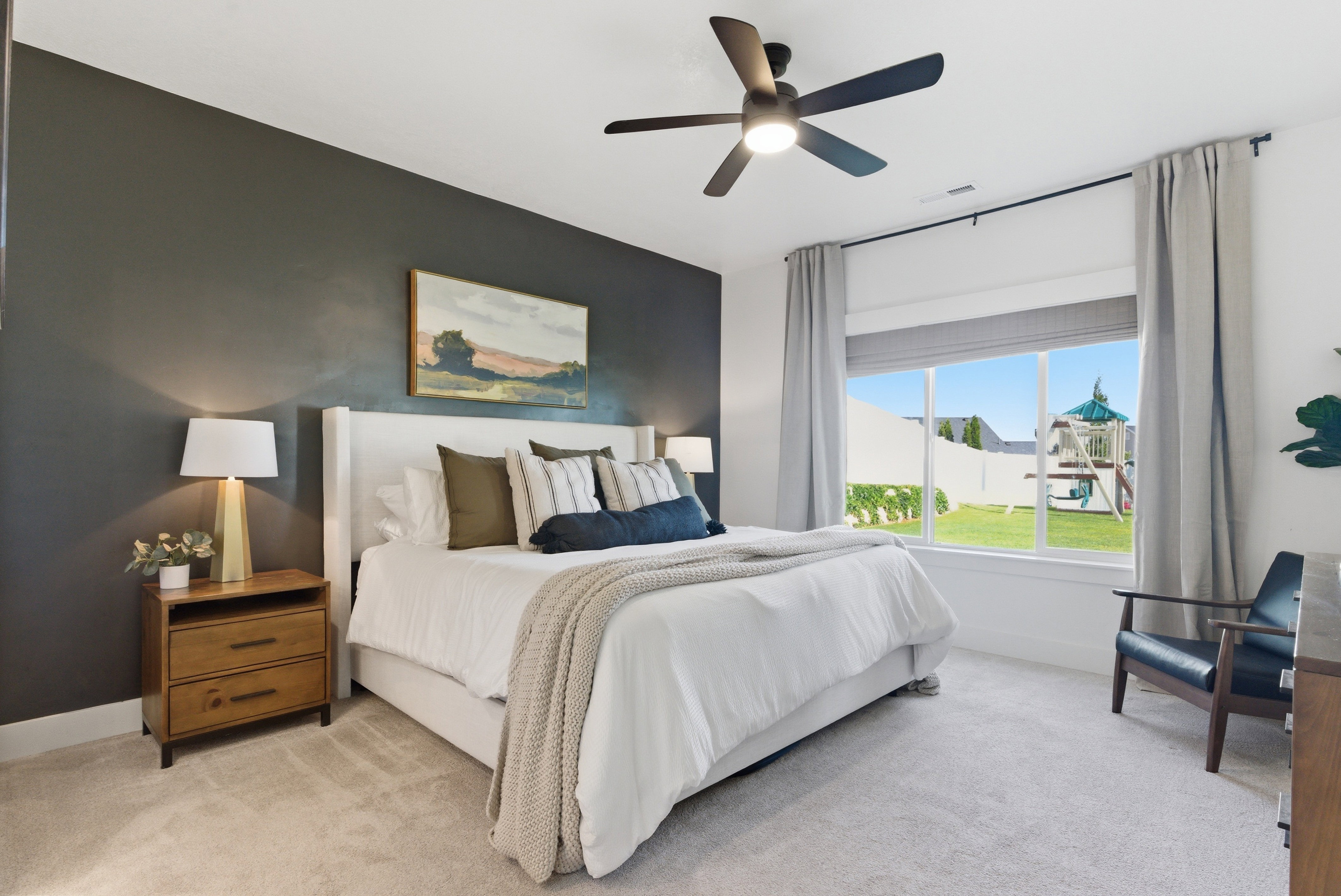 Bedroom featuring a dark accent wall, a large window, a modern ceiling fan with lighting, and light-colored carpeting