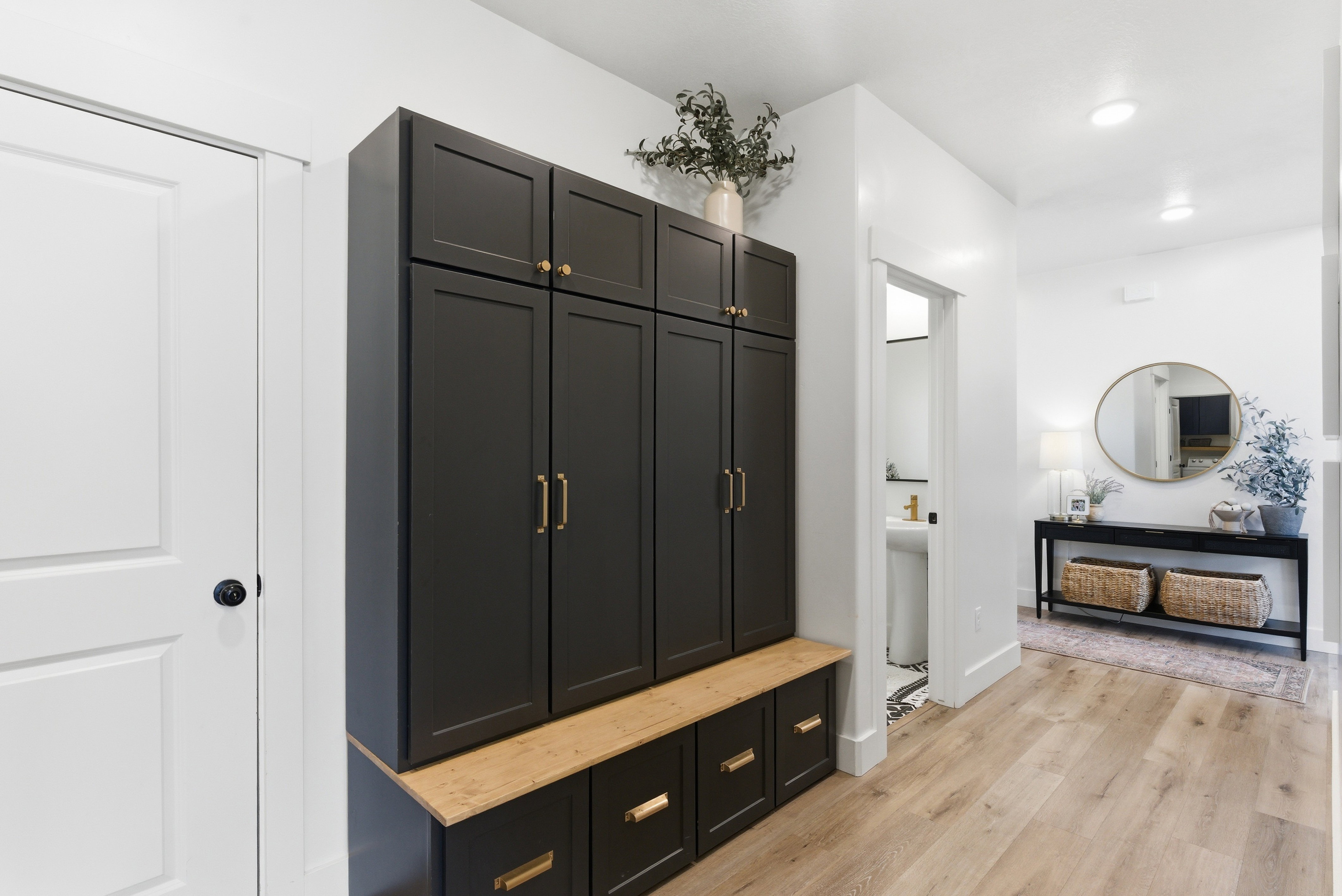 Built-in black cabinetry with gold hardware, a wood-finish bench, and integrated storage drawers