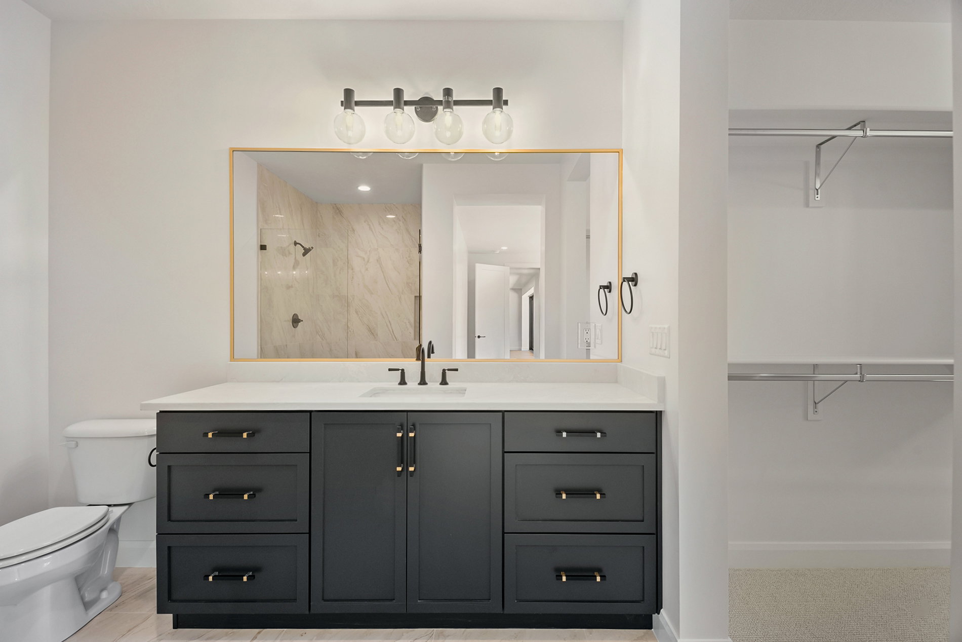 Bathroom featuring a dark vanity with a light-colored countertop, framed mirror, and a modern four-light fixture