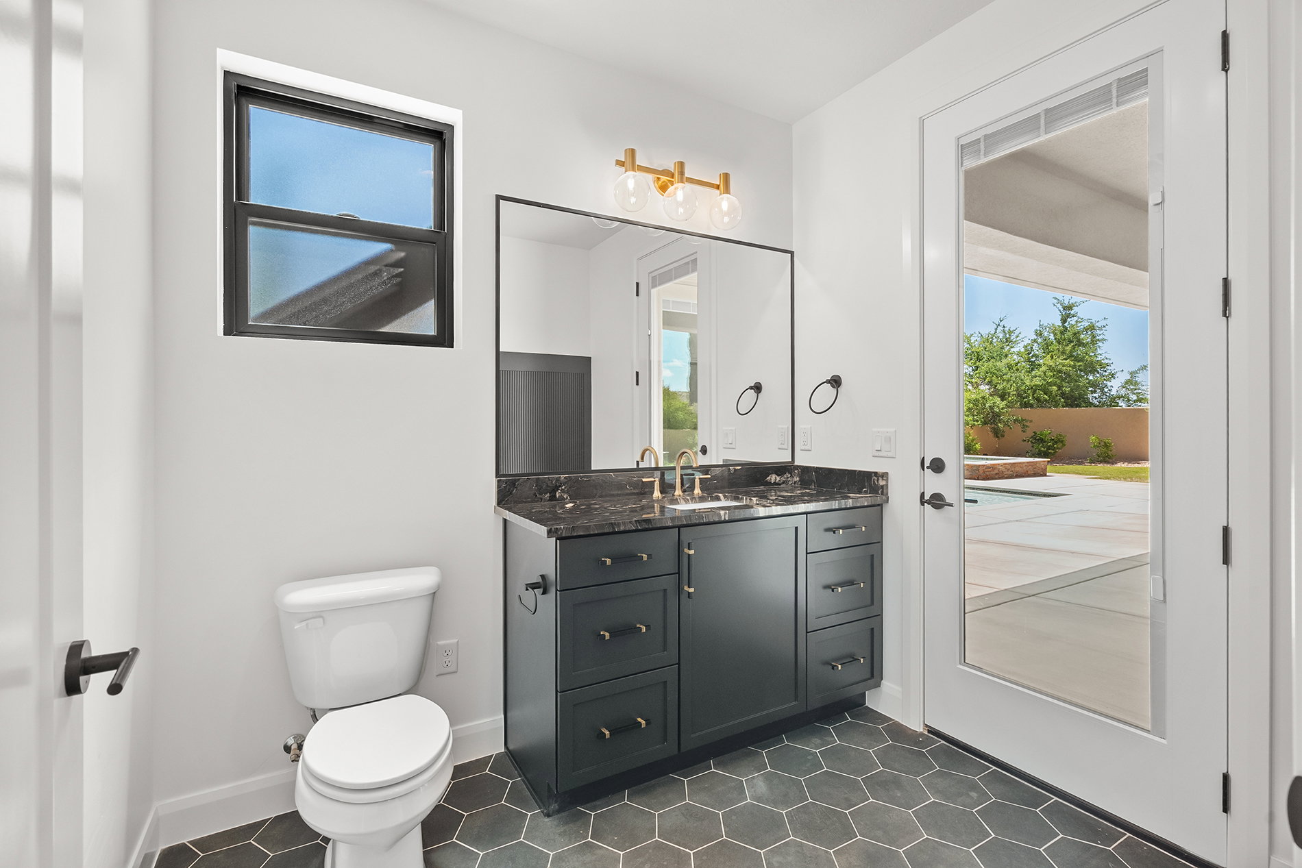 Pool Bathroom. Vanity with dark cabinetry and stone countertop