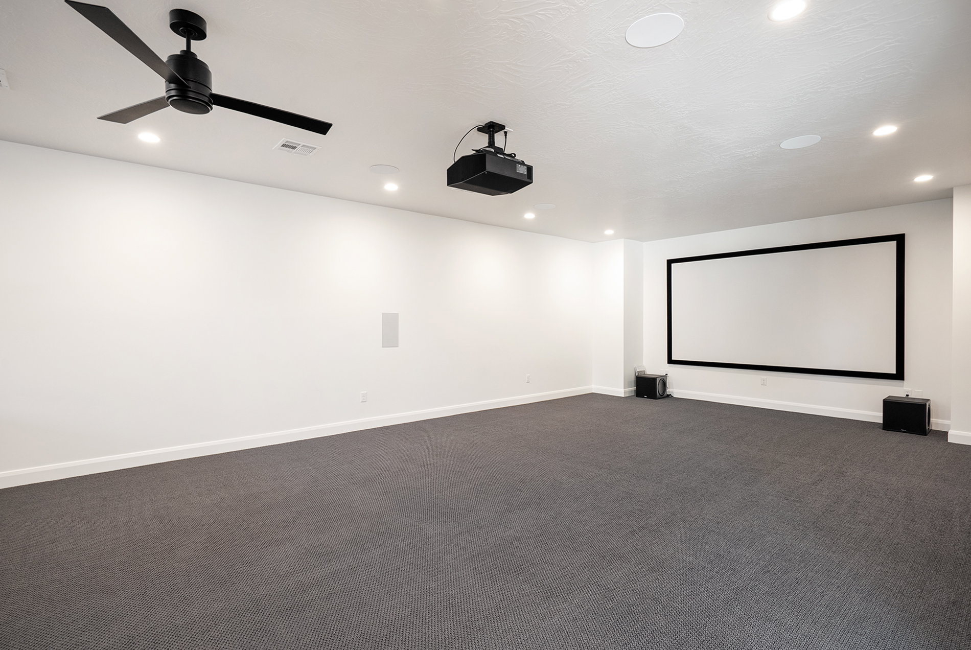 Dedicated entertainment space featuring a large projection screen, mounted projector, and recessed ceiling speakers