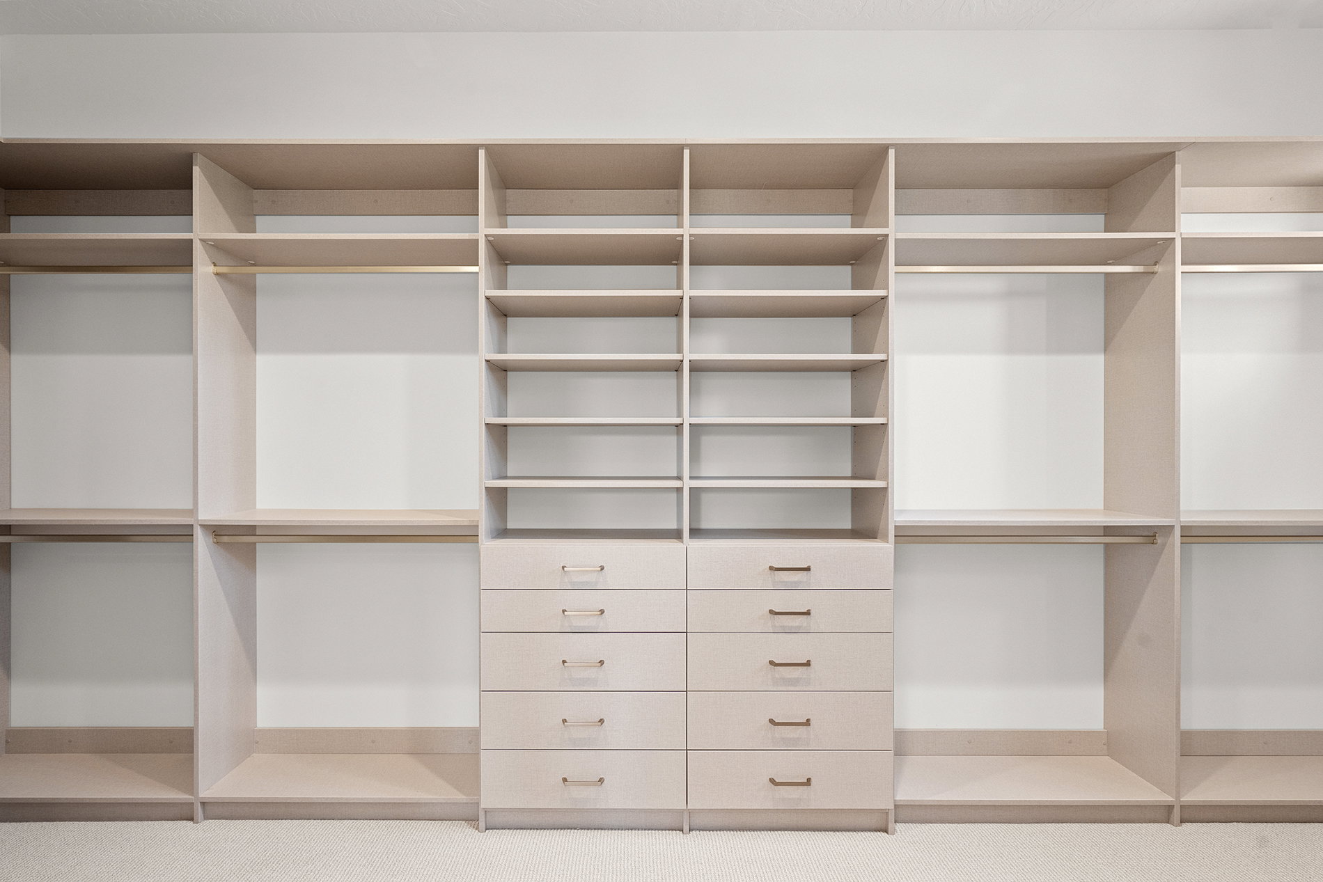 Custom closet system featuring light wood-finish cabinetry, extensive shelving, integrated hanging rods, and multiple drawers with brushed nickel hardware