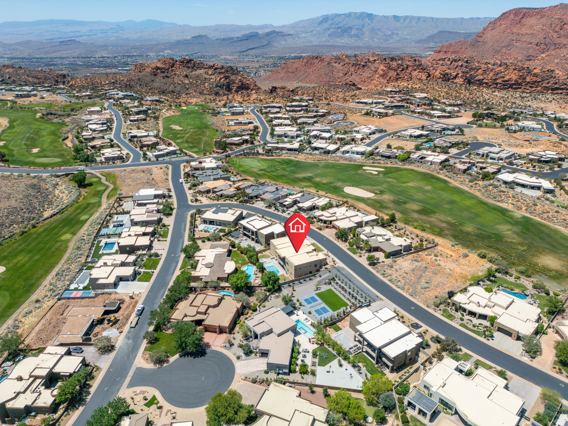 Aerial view showcasing a residential community with golf course frontage and distant mountainous terrain