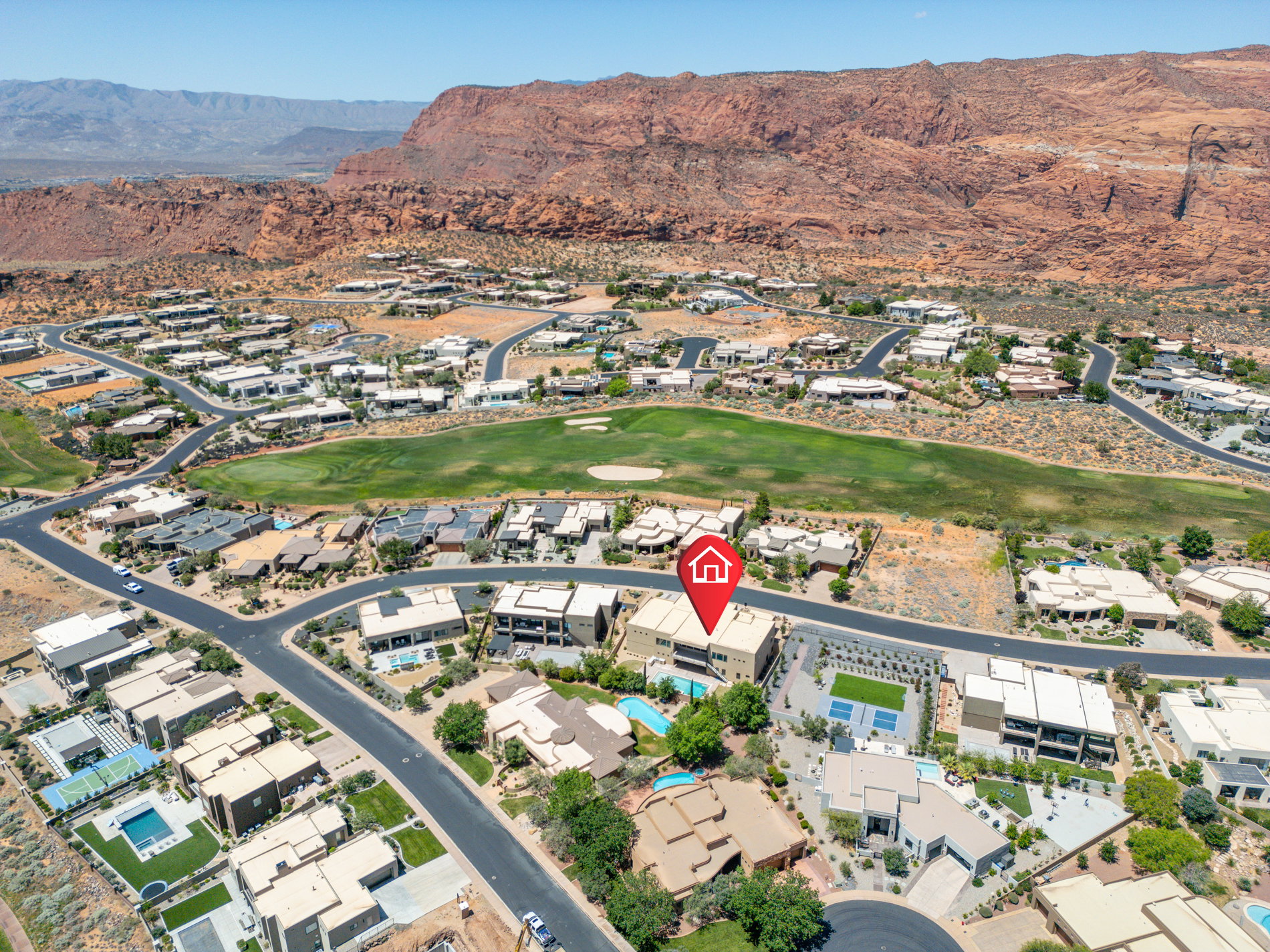 Aerial perspective showcasing a residential community with a golf course and red rock mountain backdrop