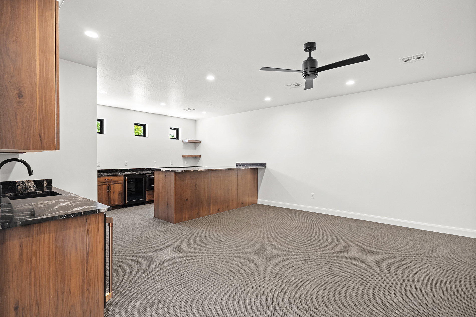 Spacious room featuring a wet bar with wood-finish cabinetry, dark countertops, and a built-in beverage refrigerator
