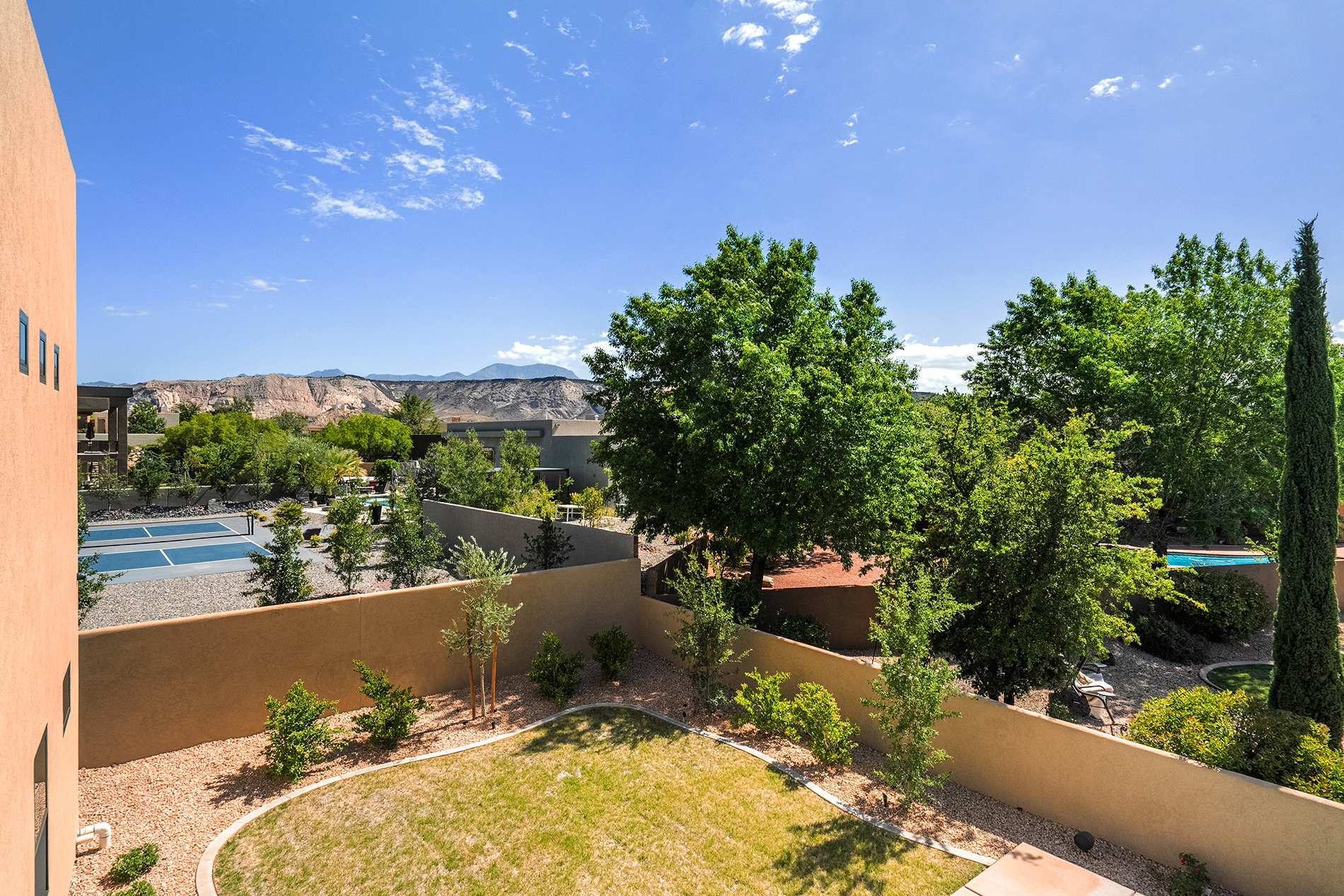 Expansive private backyard featuring a manicured lawn, established landscaping, and a surrounding privacy wall