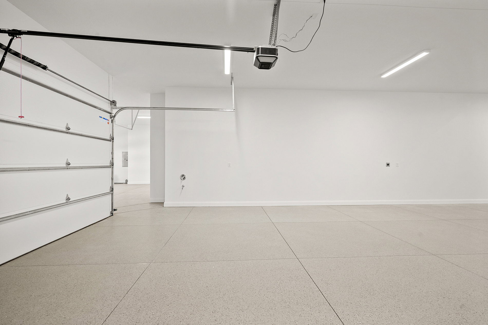 Spacious garage featuring a light-colored epoxy floor, white walls, and bright overhead lighting