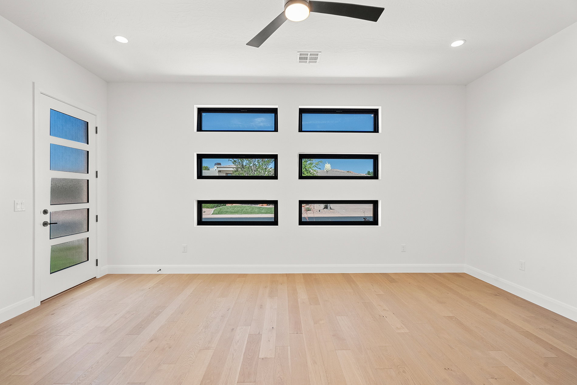 Bright interior space featuring light wood-finish flooring, recessed lighting, and a contemporary ceiling fan