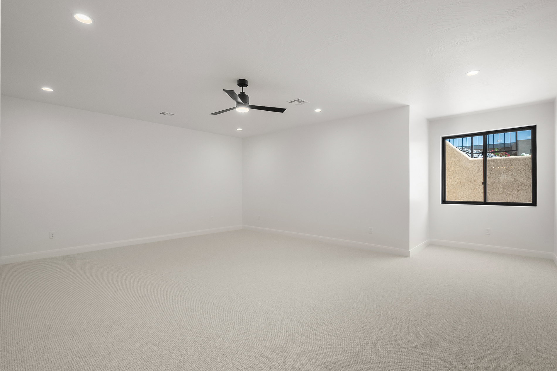 Spacious room featuring light-colored carpet flooring, recessed lighting, and a modern ceiling fan