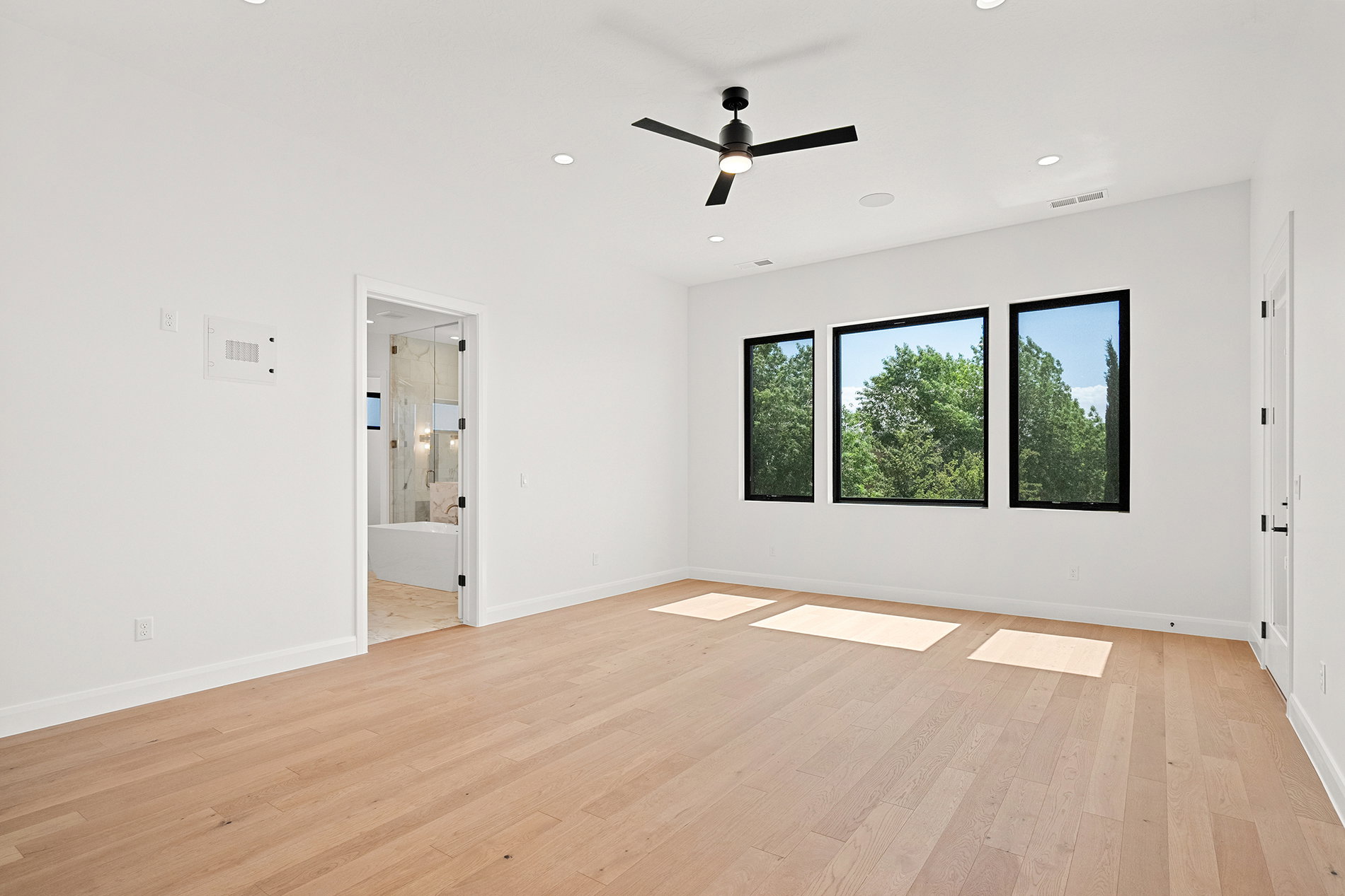 Spacious room with light wood-finish flooring, recessed lighting, and a modern ceiling fan