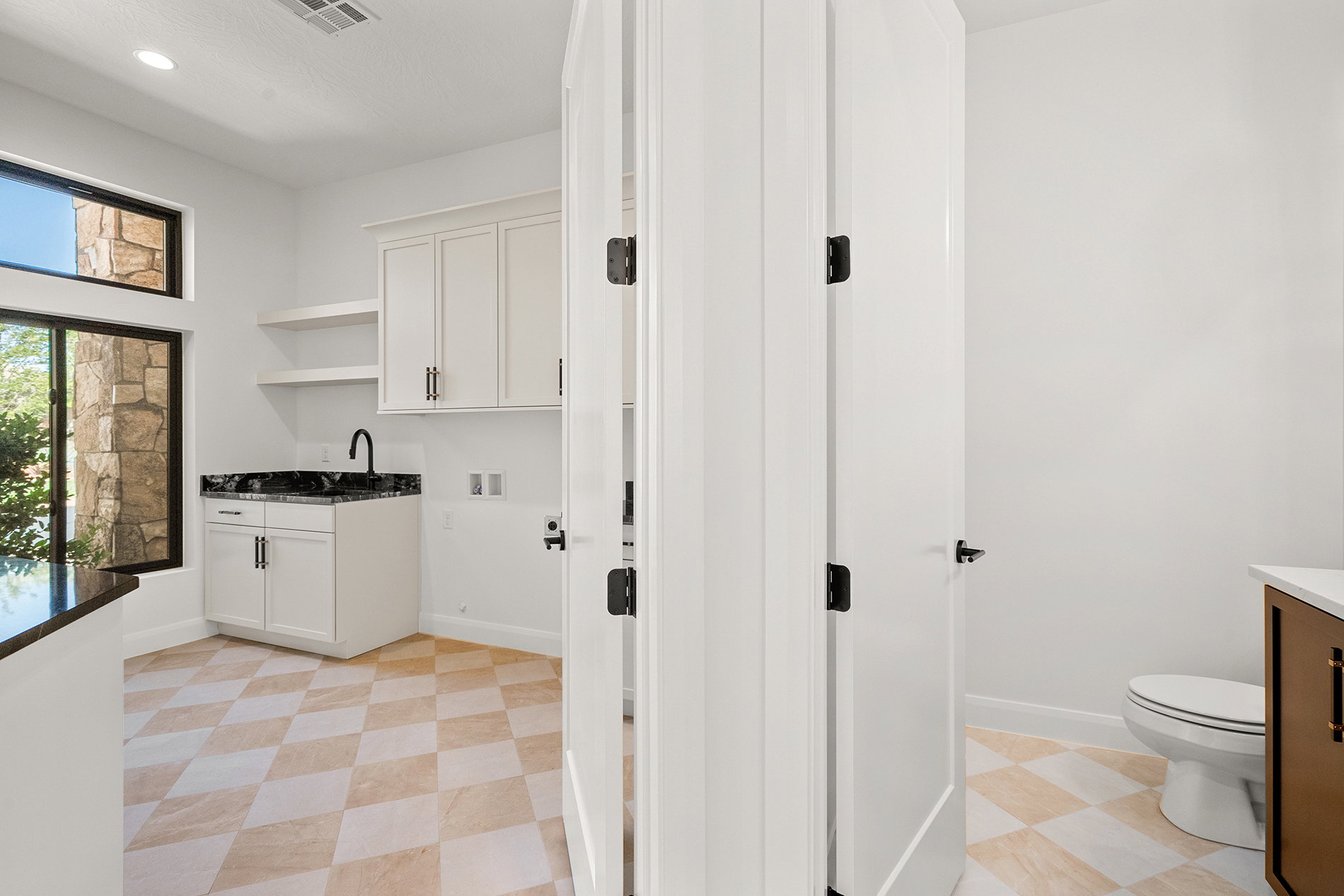 Utility room featuring white cabinetry, a dark countertop with an undermount sink, and open shelving