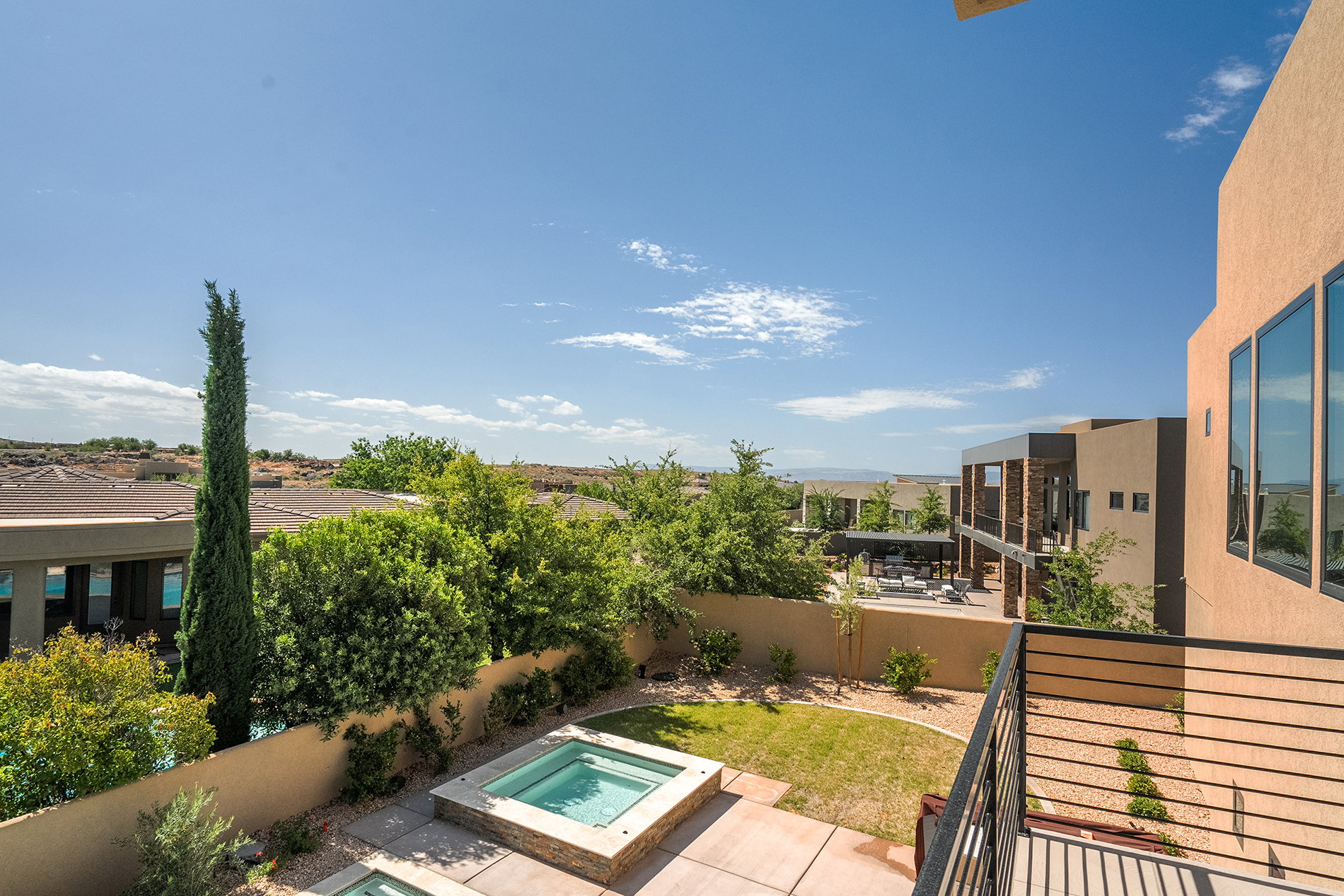 Outdoor living space featuring two in-ground spas, a manicured lawn, and mature landscaping