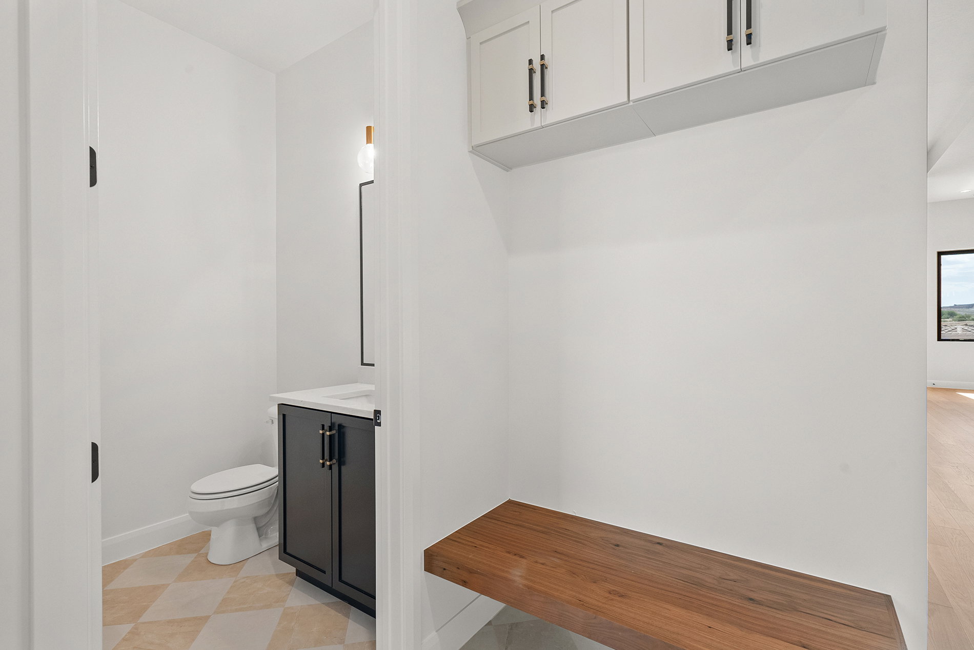 Entry area featuring a built-in wood bench and upper white cabinetry with black hardware