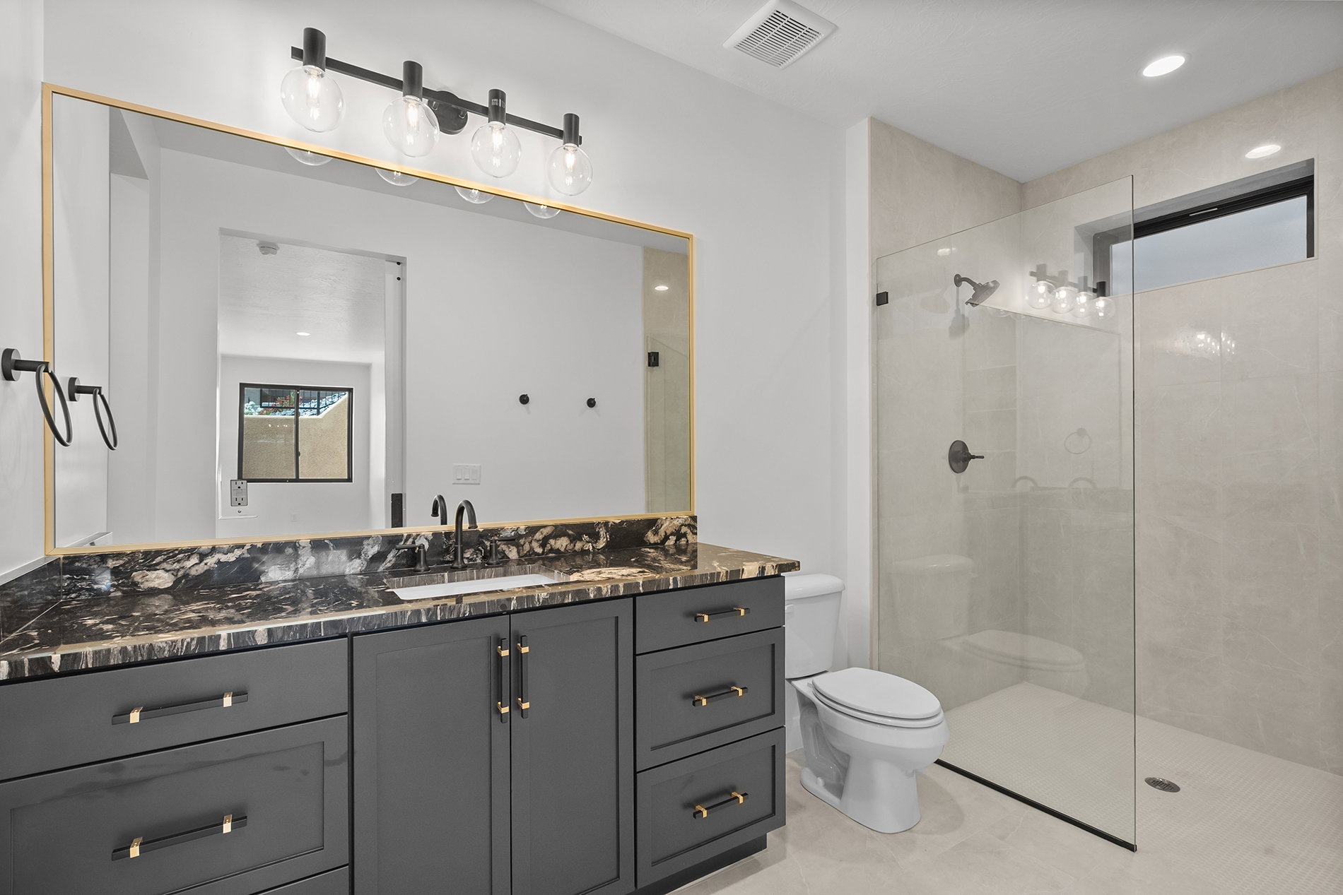Bathroom vanity featuring a black stone countertop, undermount sink, and dark cabinetry with gold-tone hardware
