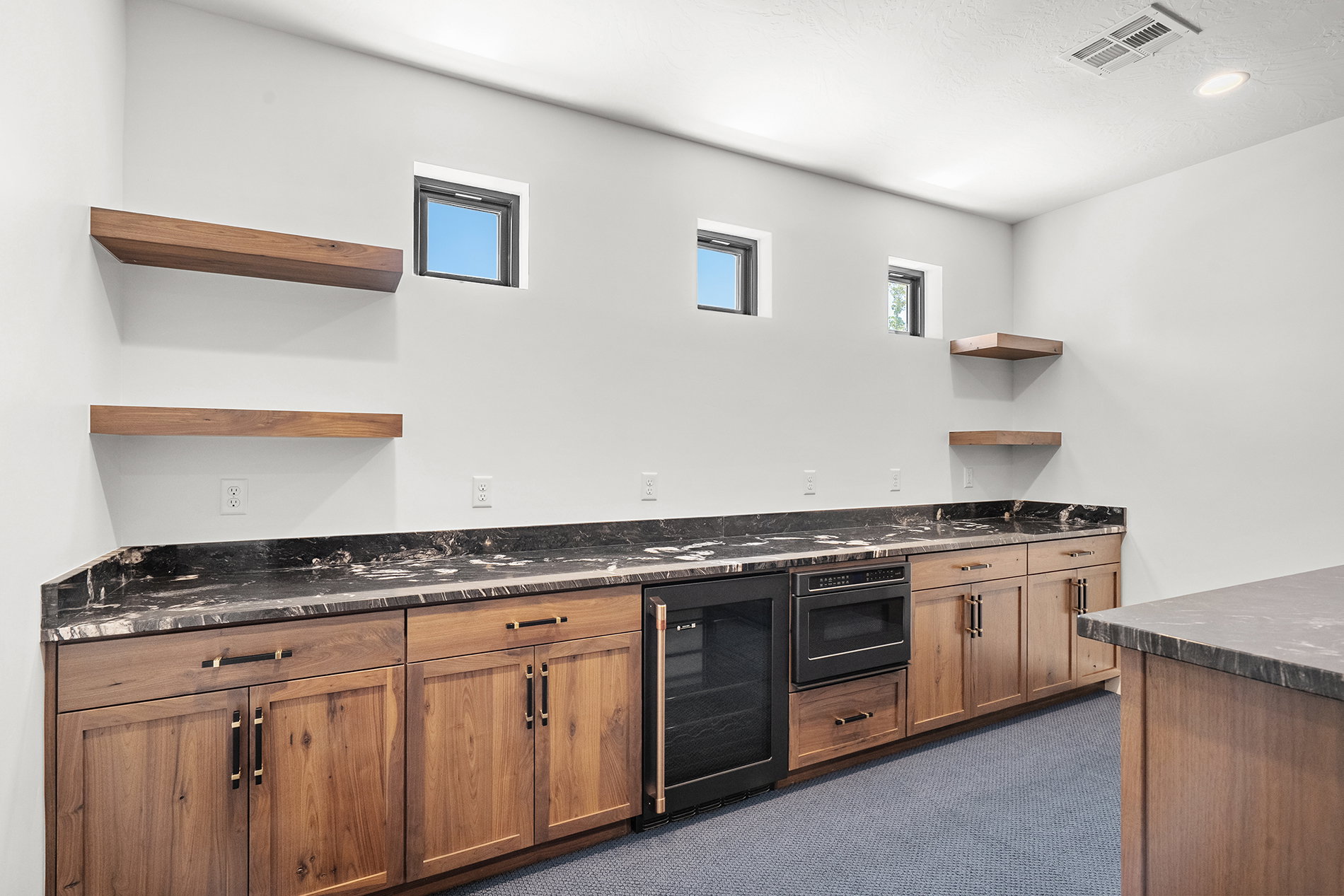 Custom cabinetry with dark hardware, stone countertops, integrated beverage cooler, and built-in microwave