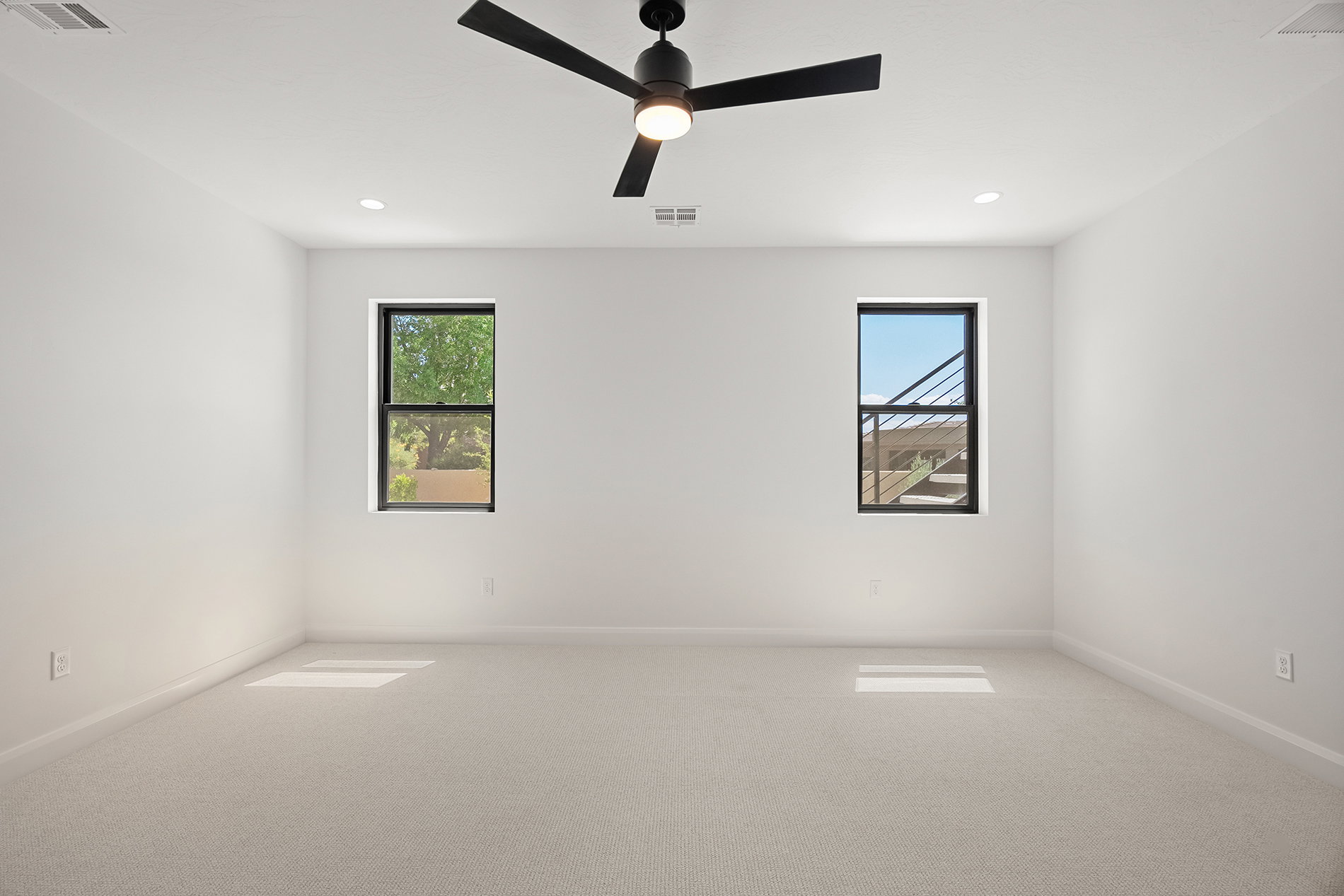 Spacious room featuring light-colored carpeting, white walls, and a ceiling fan with integrated lighting