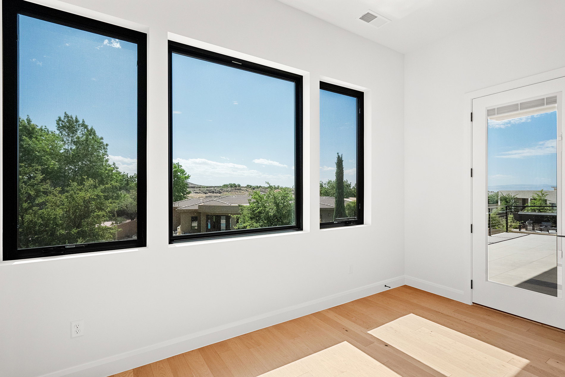 Bright interior space featuring light wood-finish flooring, white walls, and a white ceiling with a recessed vent