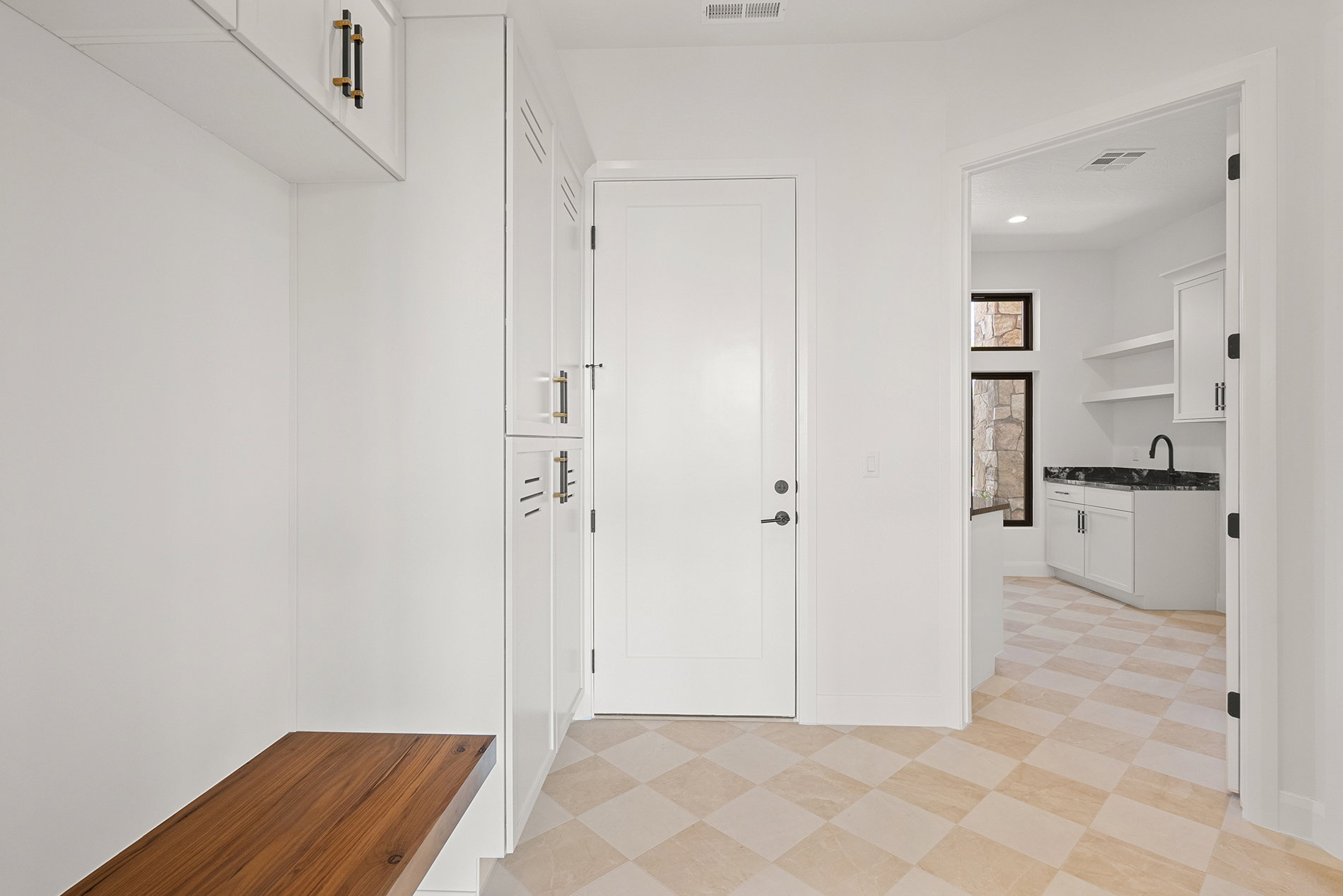 Mudroom entry featuring a built-in wood bench and white cabinetry with gold-tone hardware