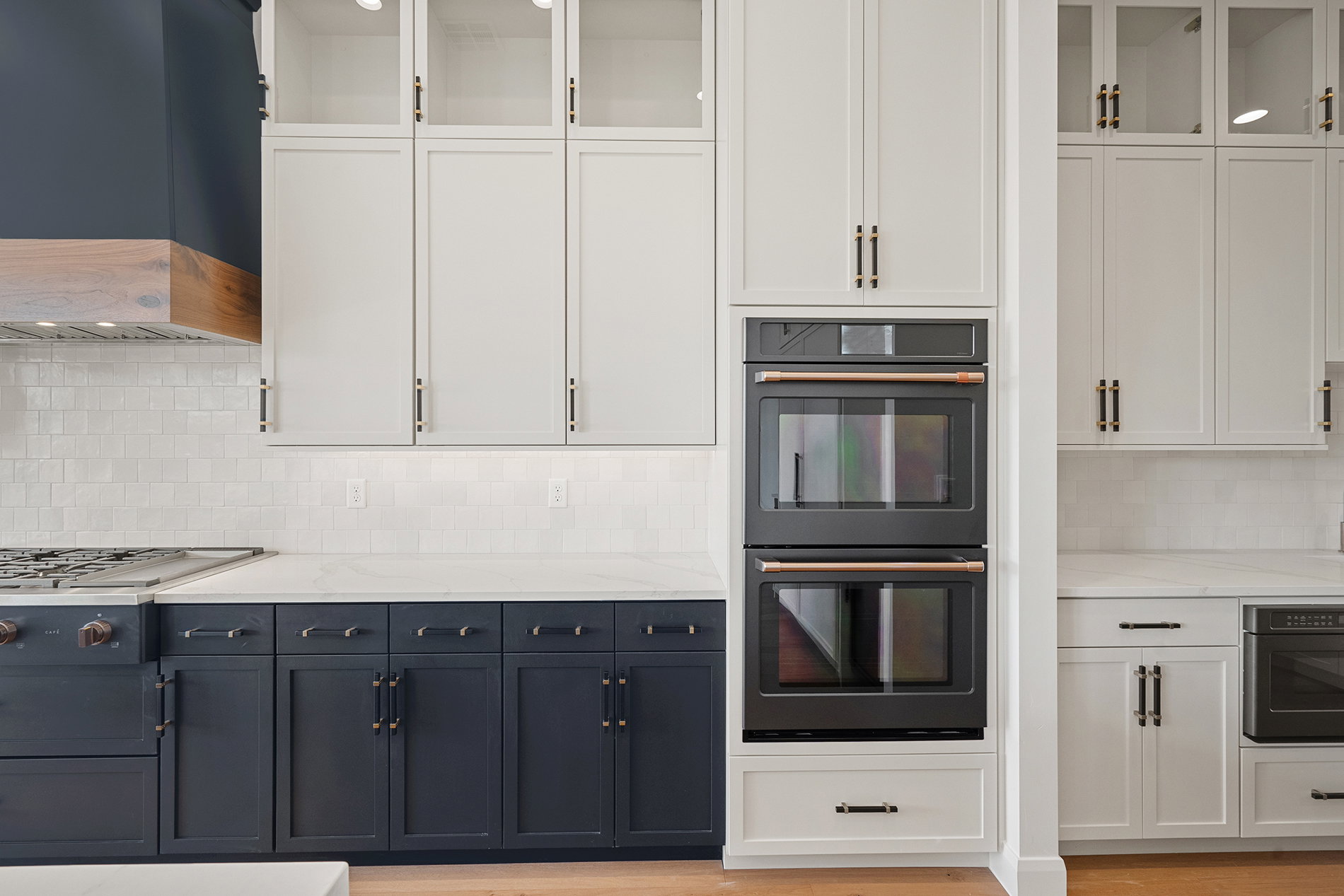 Gourmet kitchen with custom cabinetry featuring a two-tone design, built-in double ovens, and a gas range