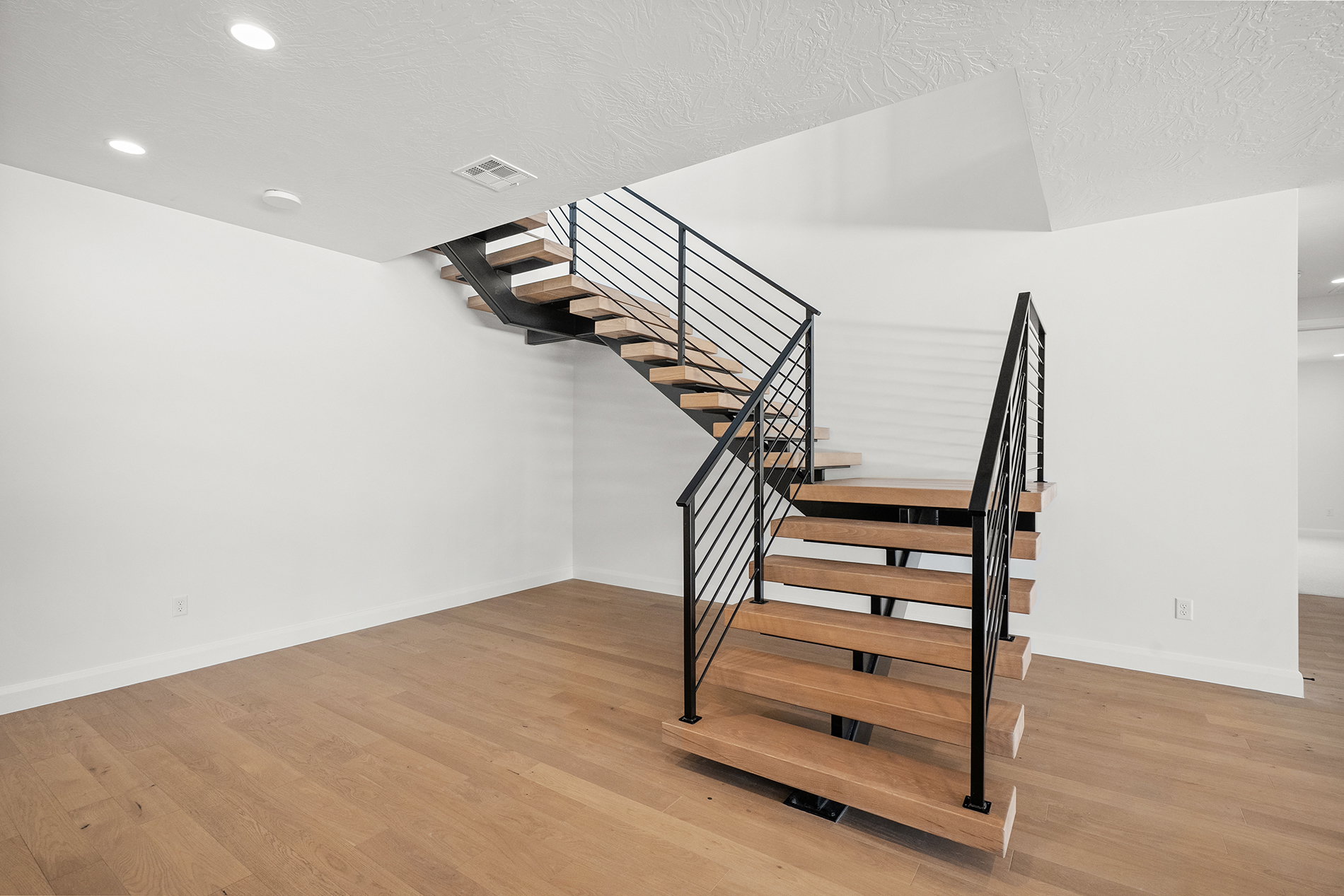 Modern open-riser staircase with wood treads and black metal railings