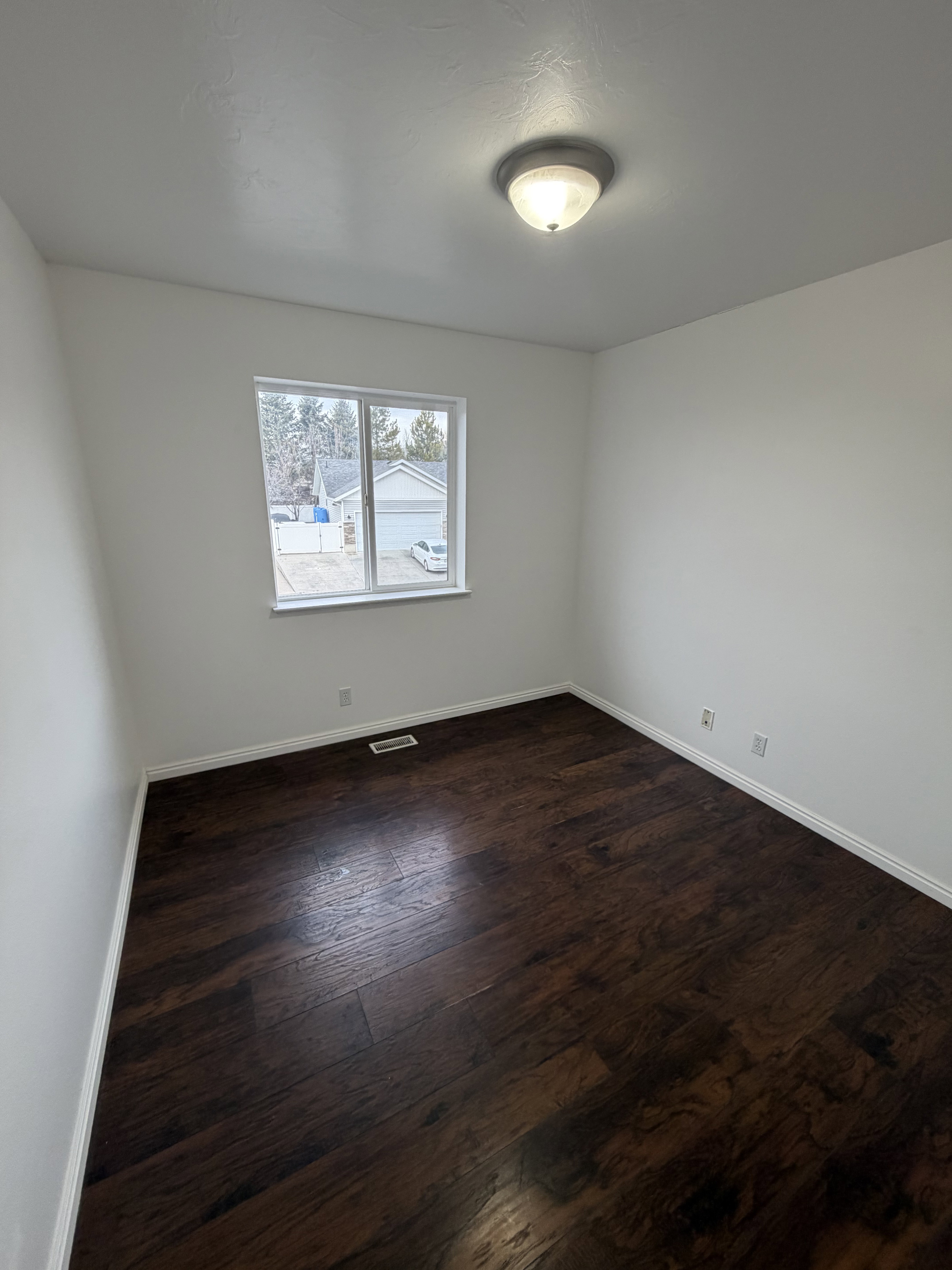Bright interior space featuring a window, dark wood-finish flooring, white baseboards, and a semi-flush mount ceiling light fixture