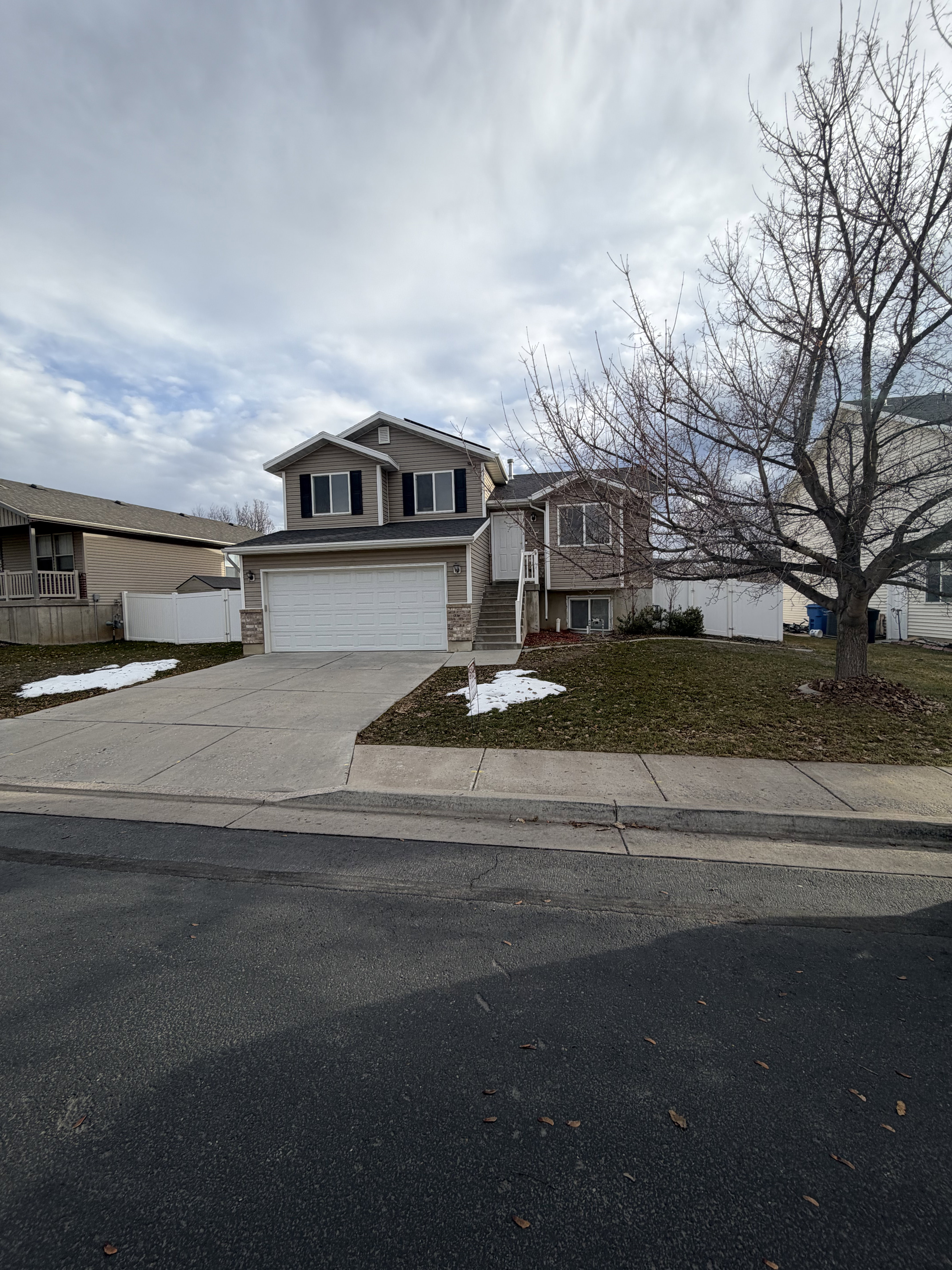 Split-level residence featuring a two-car garage, stone facade accents, and a concrete driveway