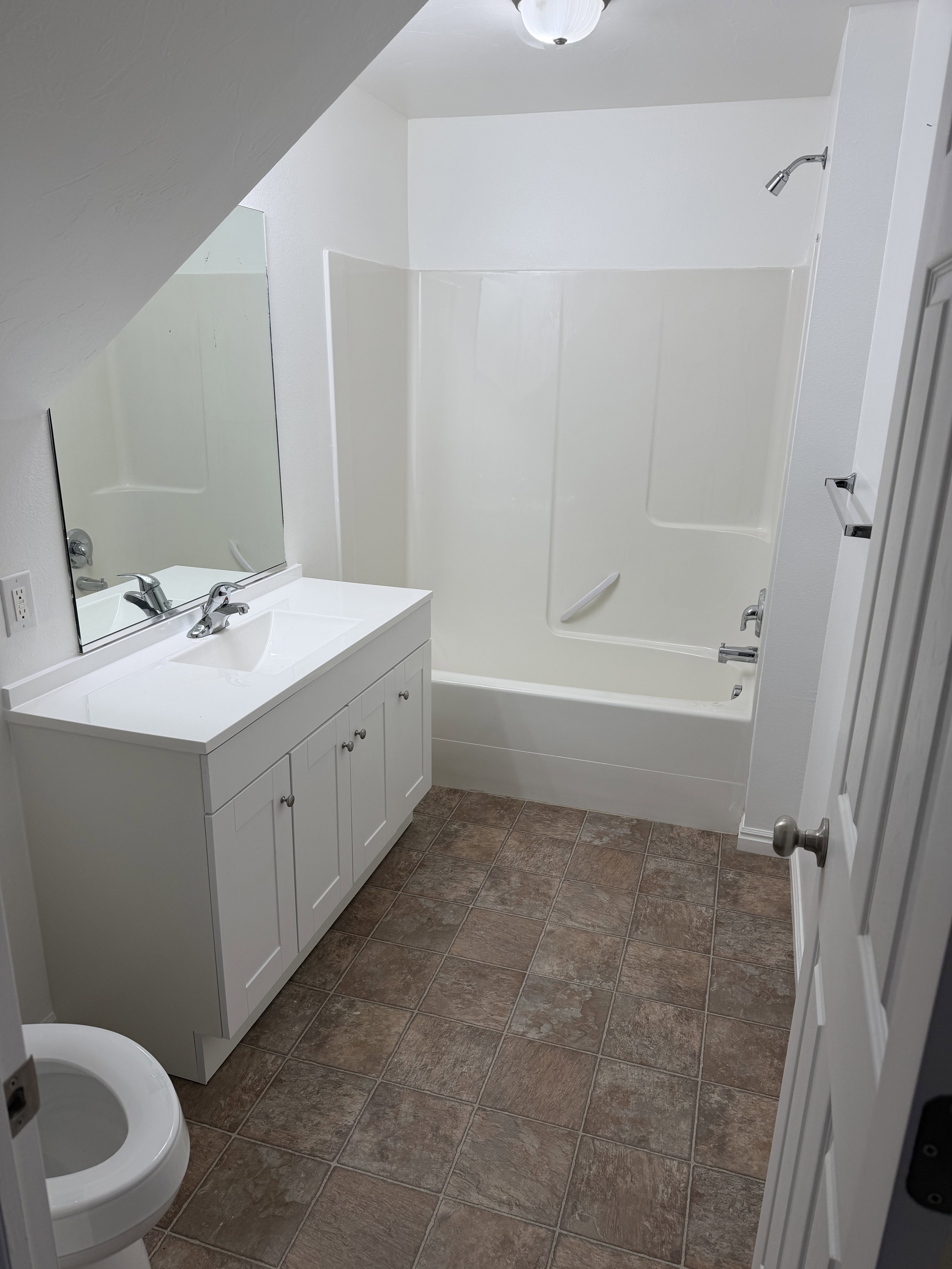 Bathroom with tile flooring, white vanity, integrated sink, and white shower-tub combination