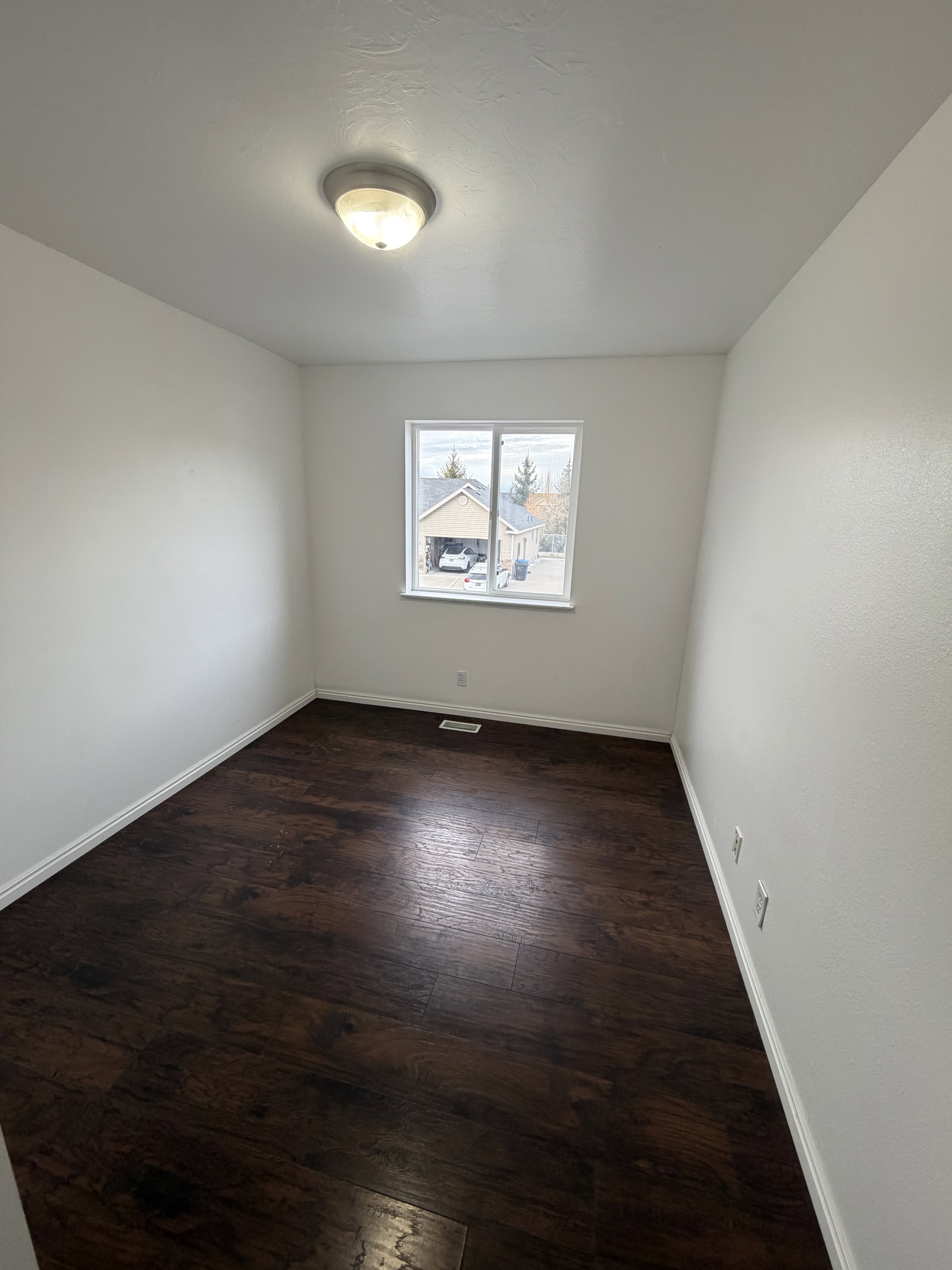 Neutral interior featuring dark wood-finish flooring and white baseboards