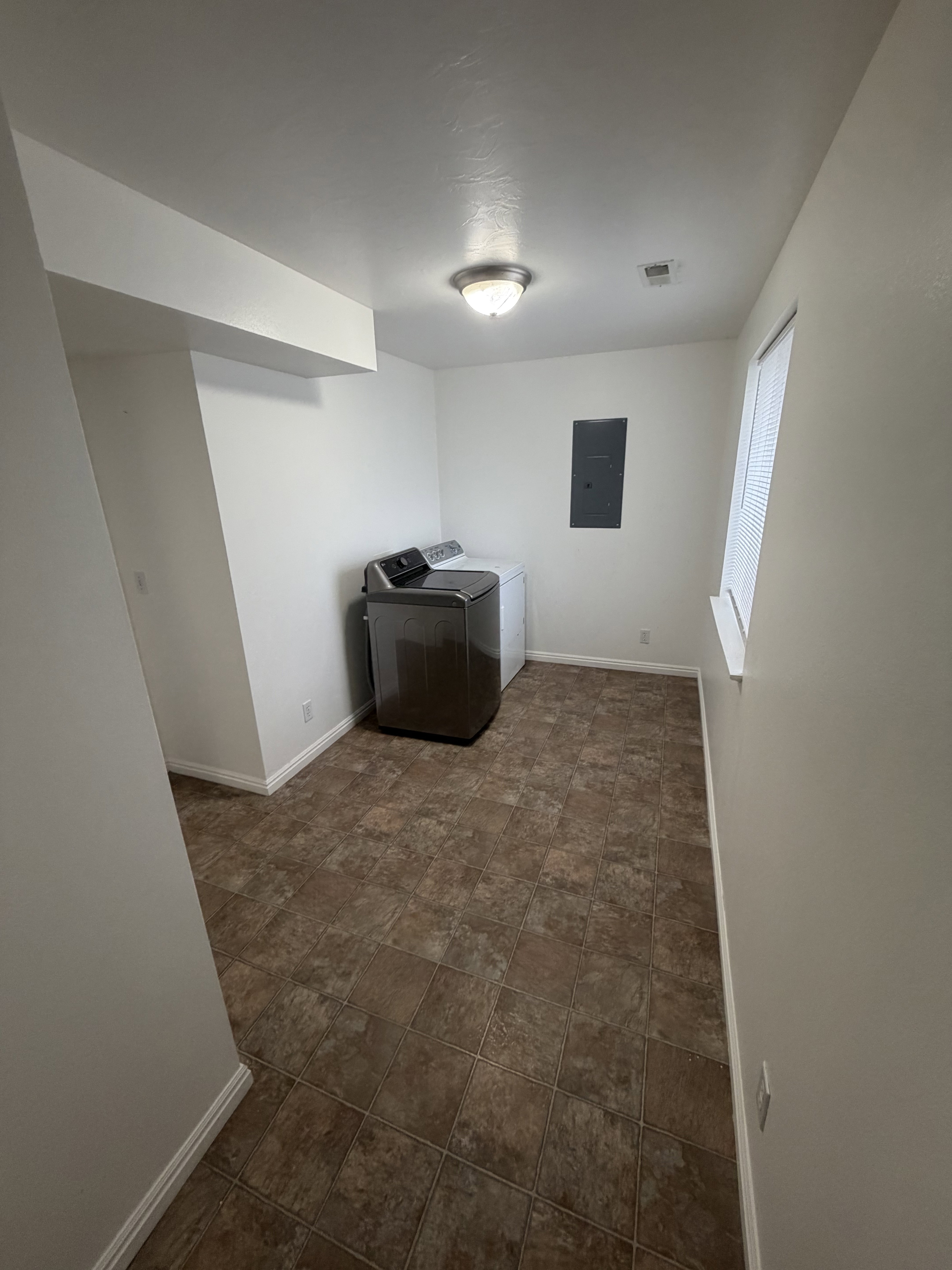 Dedicated utility area featuring tile-patterned flooring and a window with blinds