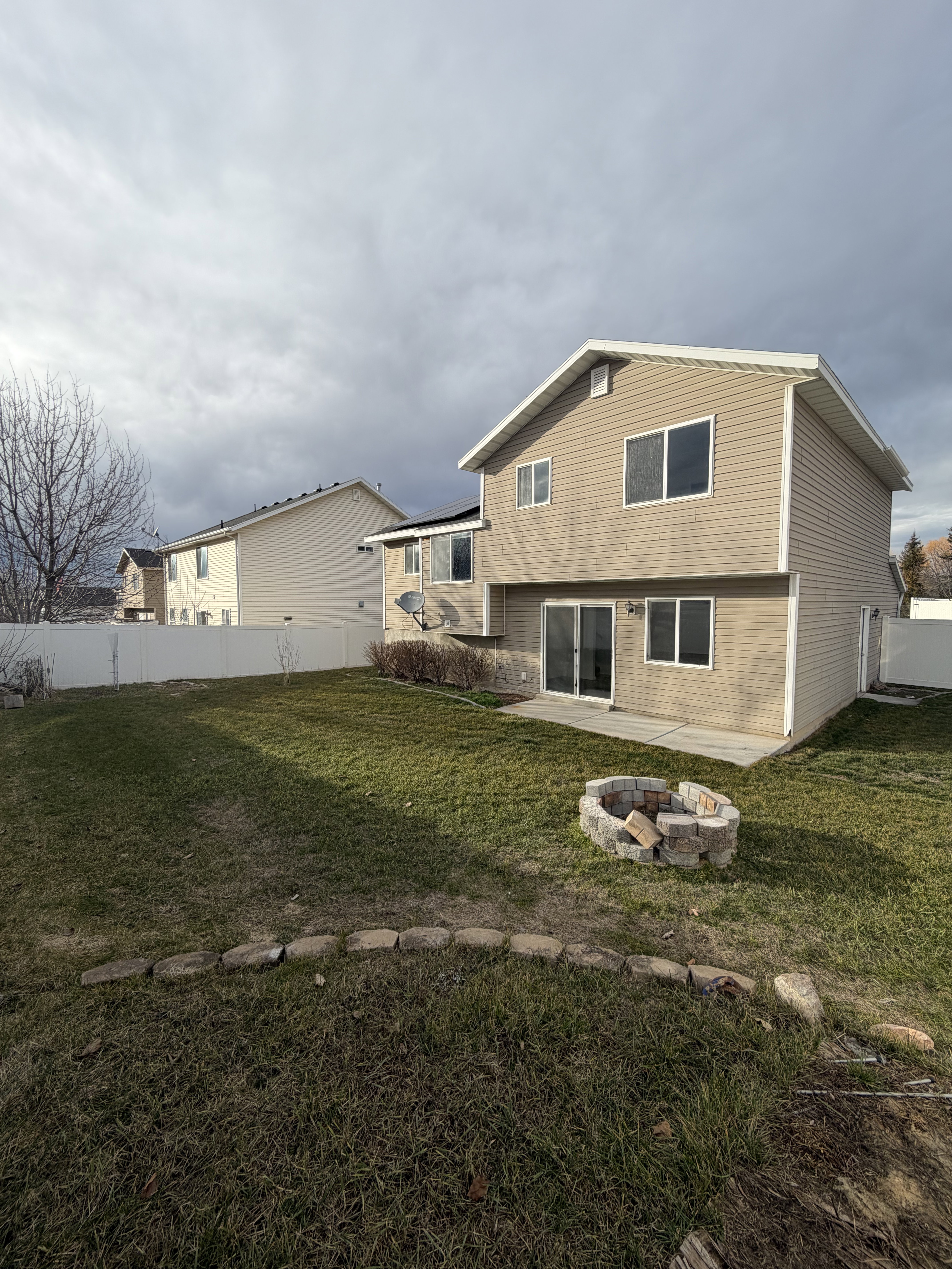 Rear exterior featuring tan horizontal siding, white trim, and a white privacy fence