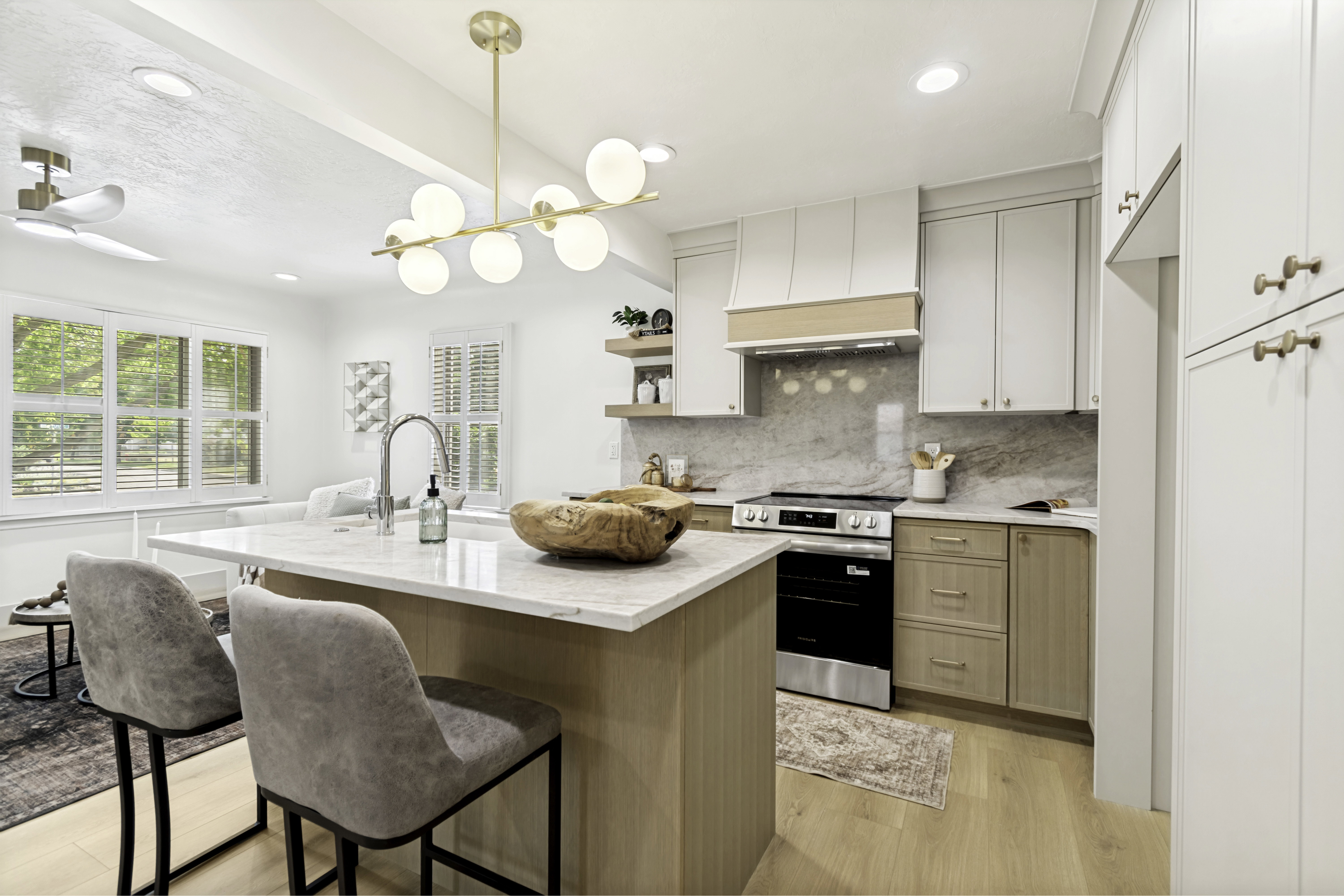 Modern kitchen featuring a central island with countertop seating, stainless steel appliances, a range hood with wood accents, and light wood-finish flooring
