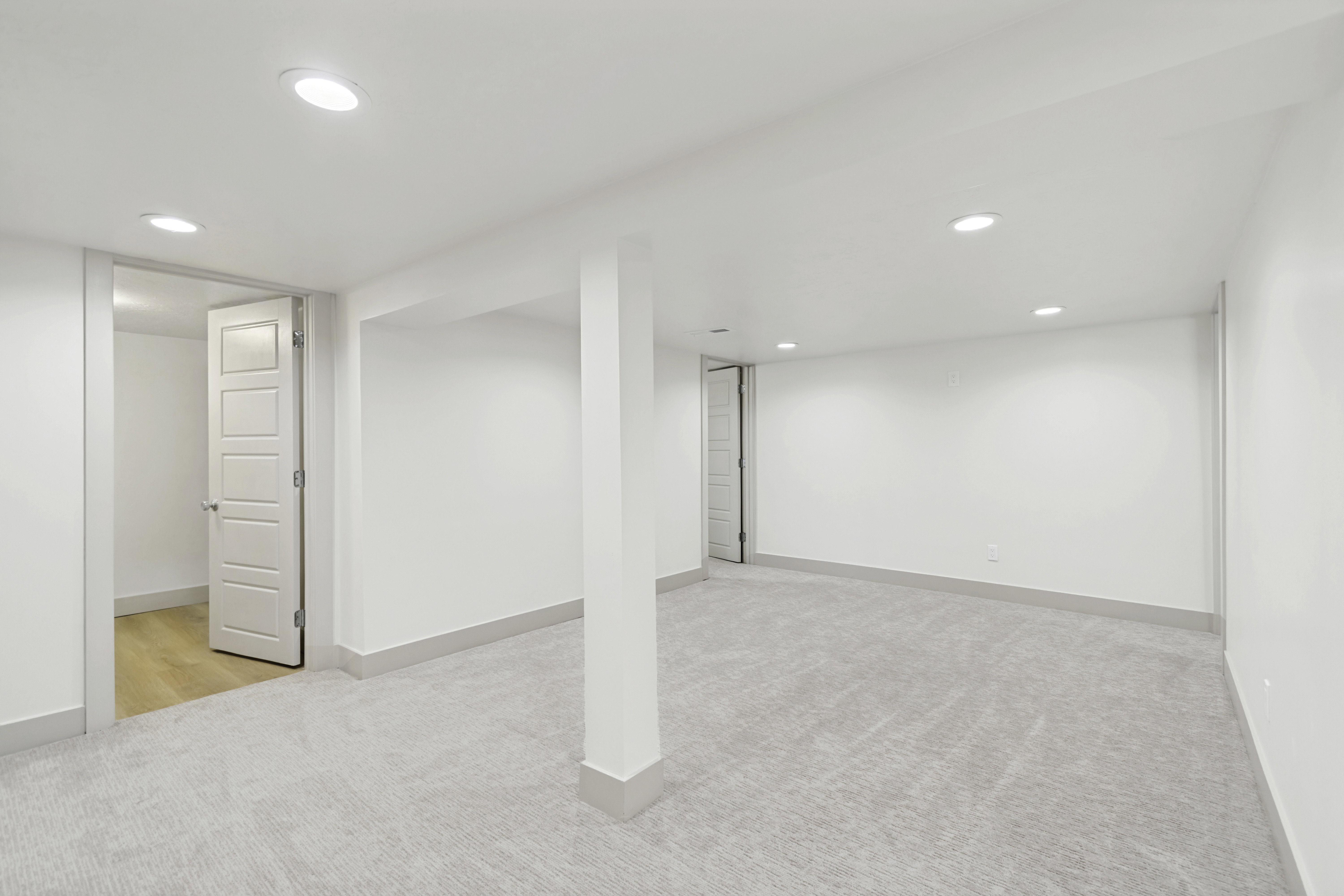 Spacious open room featuring recessed lighting, light-toned carpeting, and a white five-panel interior door