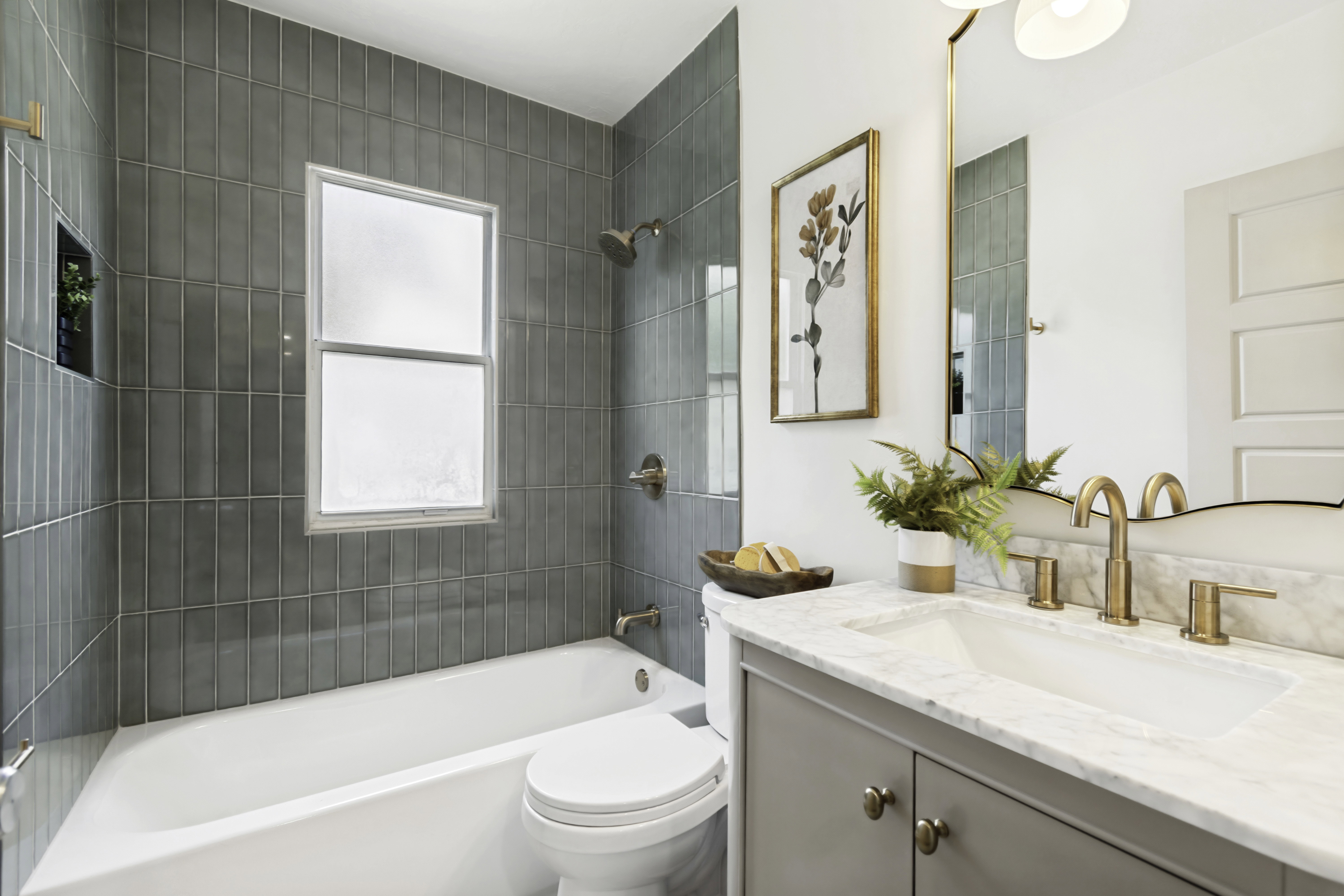 Bathroom featuring a full tub with subway tile surround, integrated shower niche, and a window with privacy glass