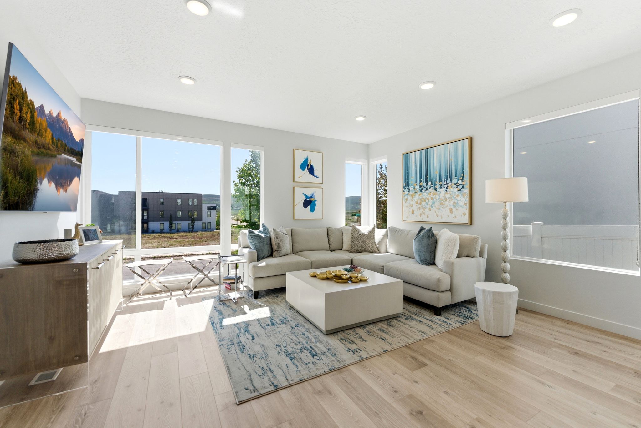 Bright living area featuring expansive windows, recessed lighting, wood-finish flooring, and a light color palette
