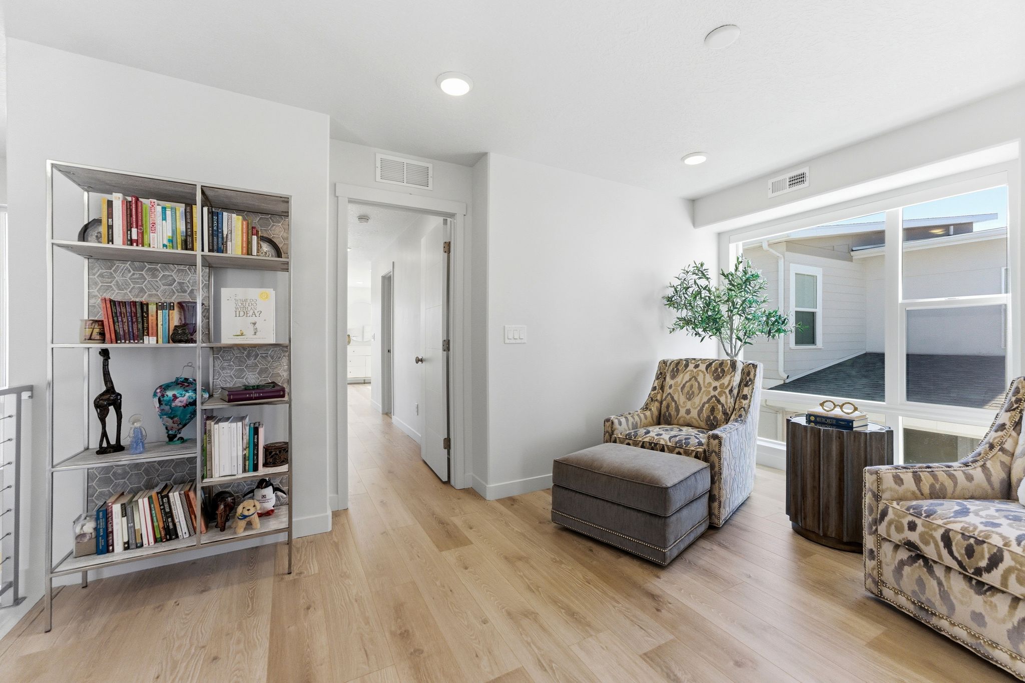 Bright interior space featuring light wood-finish flooring, a built-in shelving unit with a hexagonal tile backing, and recessed lighting